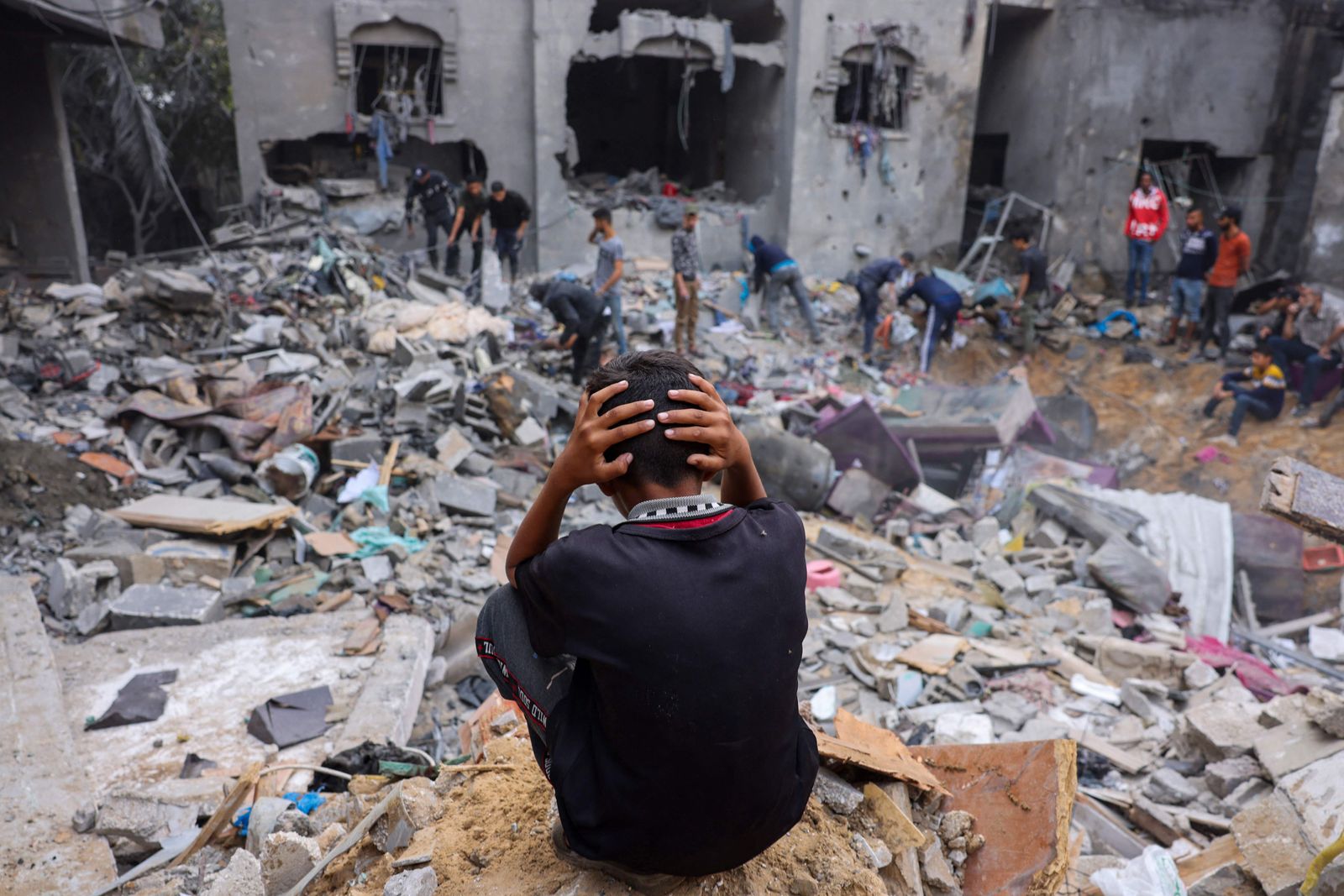 A child reacts as people salvage belongings from a damaged building following strikes on Rafah in the southern Gaza Strip, on November 12, 2023, as battles between Israel and the Palestinian Hamas movement continue. More than 10,000 people have been killed in relentless Israeli bombardment of the Gaza Strip, according to the Hamas-run health ministry, since the war erupted last month after Palestnian militants raided southern Israel on October 7 killing at least 1200 people. (Photo by Mohammed ABED / AFP)