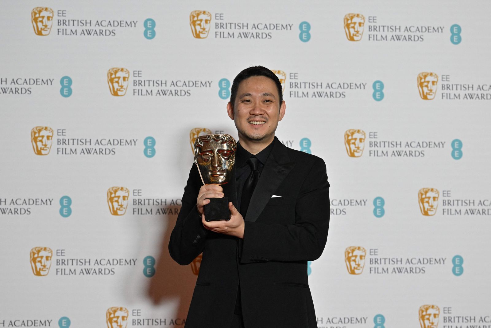 Japanese director Ryusuke Hamaguchi poses with the award for a Film Not In The English Language for 'Drive My Car' shared with and Japanese producer Teruhisa Yamamoto (not pictured) at the BAFTA British Academy Film Awards at the Royal Albert Hall in London on March 13, 2022. (Photo by Ben Stansall / AFP) - AFP