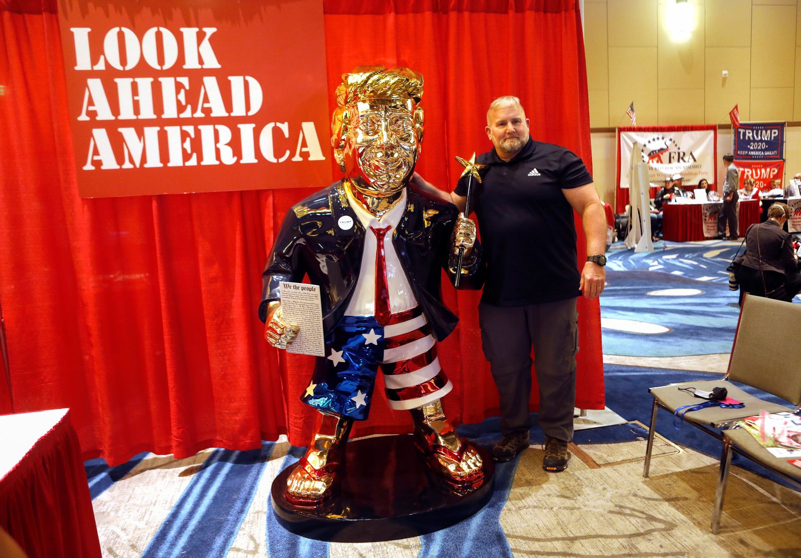 أحد المشاركين في مؤتمر العمل السياسي المحافظ يأخذ صورة مع تمثال ذهبي للرئيس السابق دونالد ترمب - REUTERS