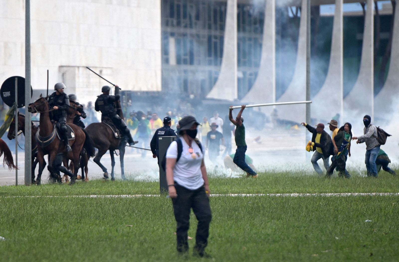 Supporters of Brazilian former President Jair Bolsonaro clash with security forces during an invasion to Planalto Presidential Palace in Brasilia on January 8, 2023. - Hundreds of supporters of Brazil's far-right ex-president Jair Bolsonaro broke through police barricades and stormed into Congress, the presidential palace and the Supreme Court Sunday, in a dramatic protest against President Luiz Inacio Lula da Silva's inauguration last week. (Photo by Ton MOLINA / AFP) - AFP