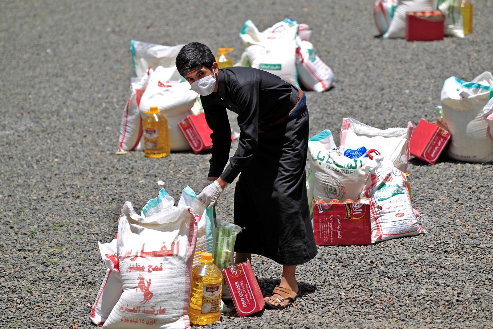 شاب يمني يحمل مساعدات غذائية في العاصمة اليمنية صنعاء - AFP