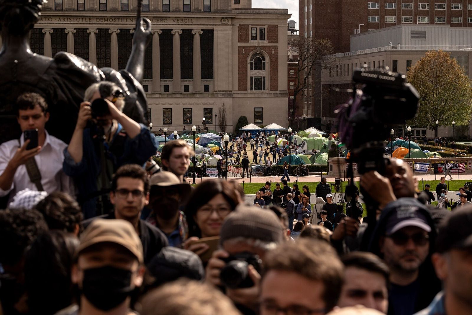 Pro-Palestinian demonstrators, back, at an encampment as US House Speaker Mike Johnson, a Republican from Louisiana, not pictured, speaks during a news conference outside the Lower Library at Columbia University in the Morningside Heights neighborhood of New York, US, on Wednesday, April 24, 2024. Johnson on Wednesday called on Columbia University president Minouche Shafik to resign, stating that they cannot guarantee the safety of Jewish students on campus. Photographer: Yuki Iwamura/Bloomberg