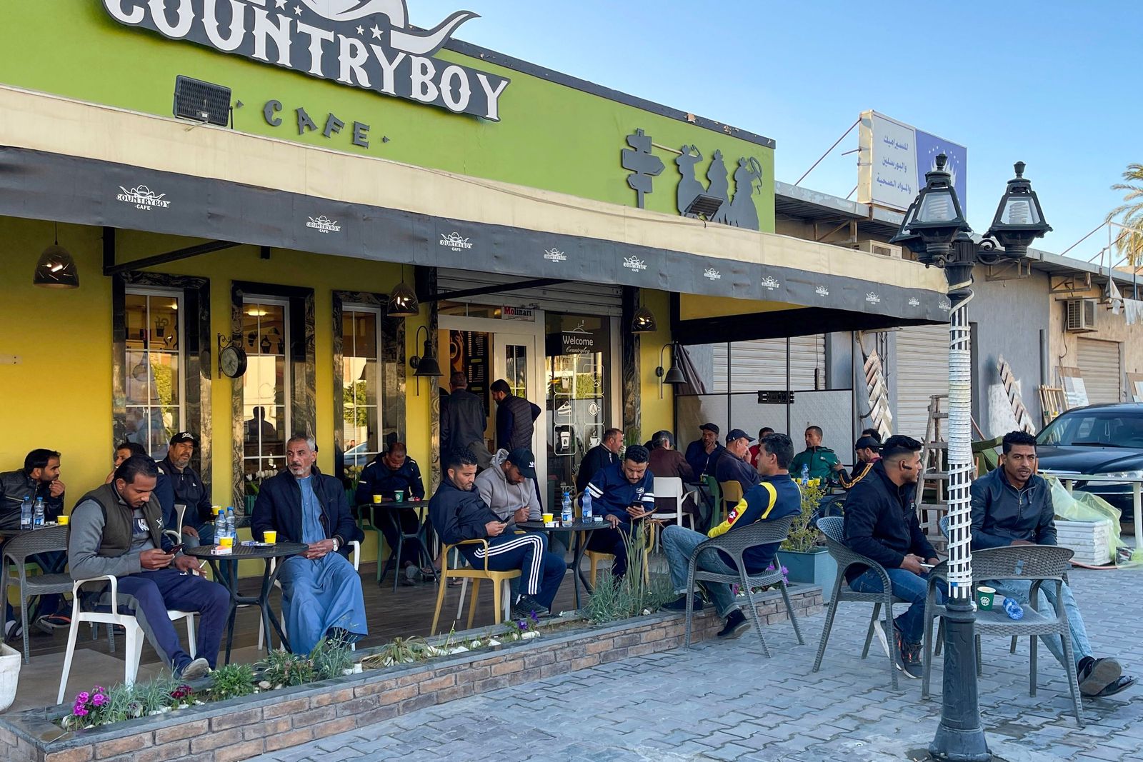 In this picture taken on March 17, 2023, people sit outside a coffee shop in Tripoli. - Italy left a deep cultural mark on Libya, the only Arab country it colonised: a national love of espresso. But as the fasting month of Ramadan approaches, Libyans are preparing to go without. Throughout the Islamic holy month, which is due to begin this week, observant Muslims are expected to refrain from eating and drinking from dawn to dusk. (Photo by Mahmud TURKIA / AFP) - AFP