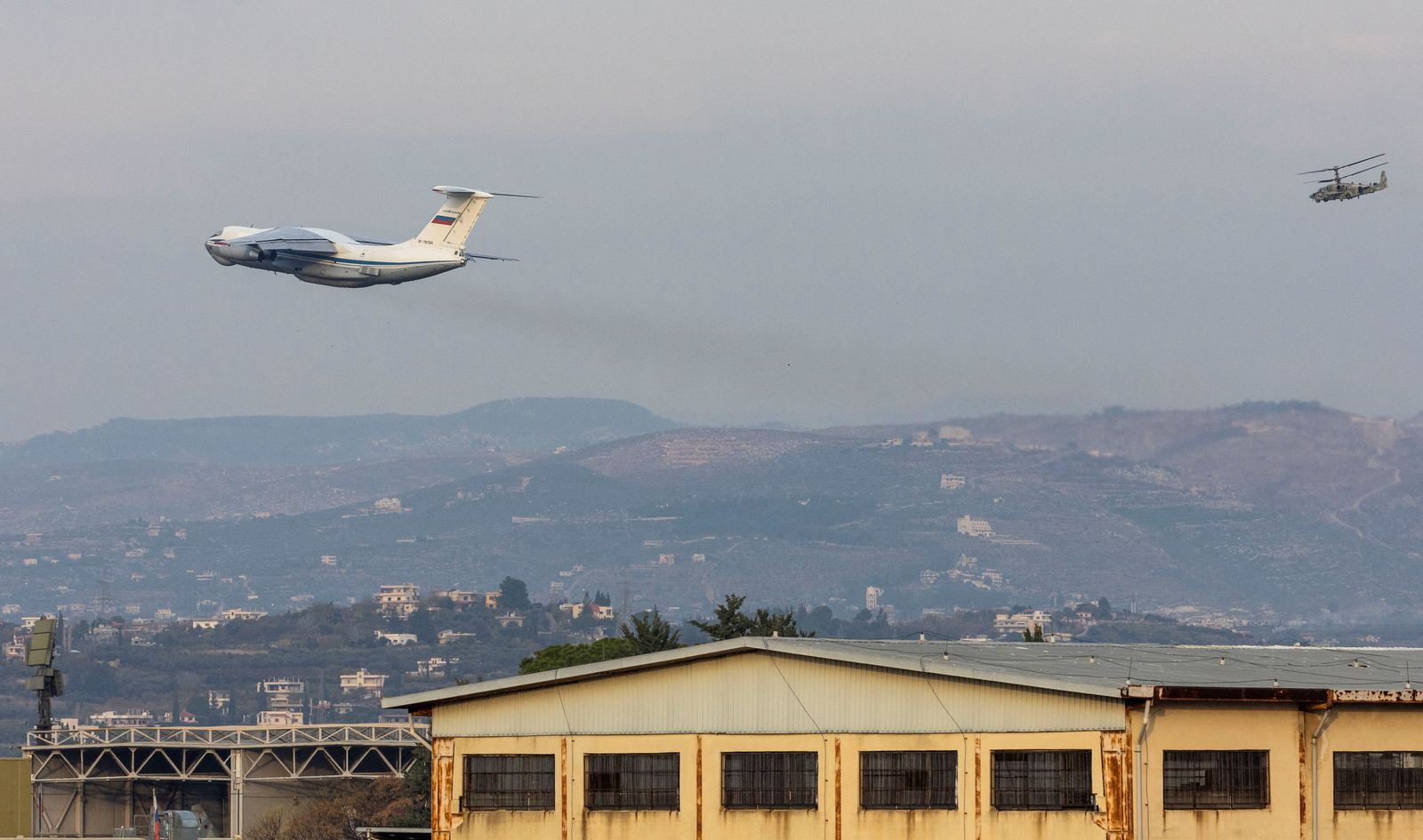 A Russian military aircraft takes off from Hmeimim air base as a Russian military helicopter Kamov KA-50 flies over the base in Syria's coastal Latakia, Syria, December 15, 2024. REUTERS/Umit Bektas