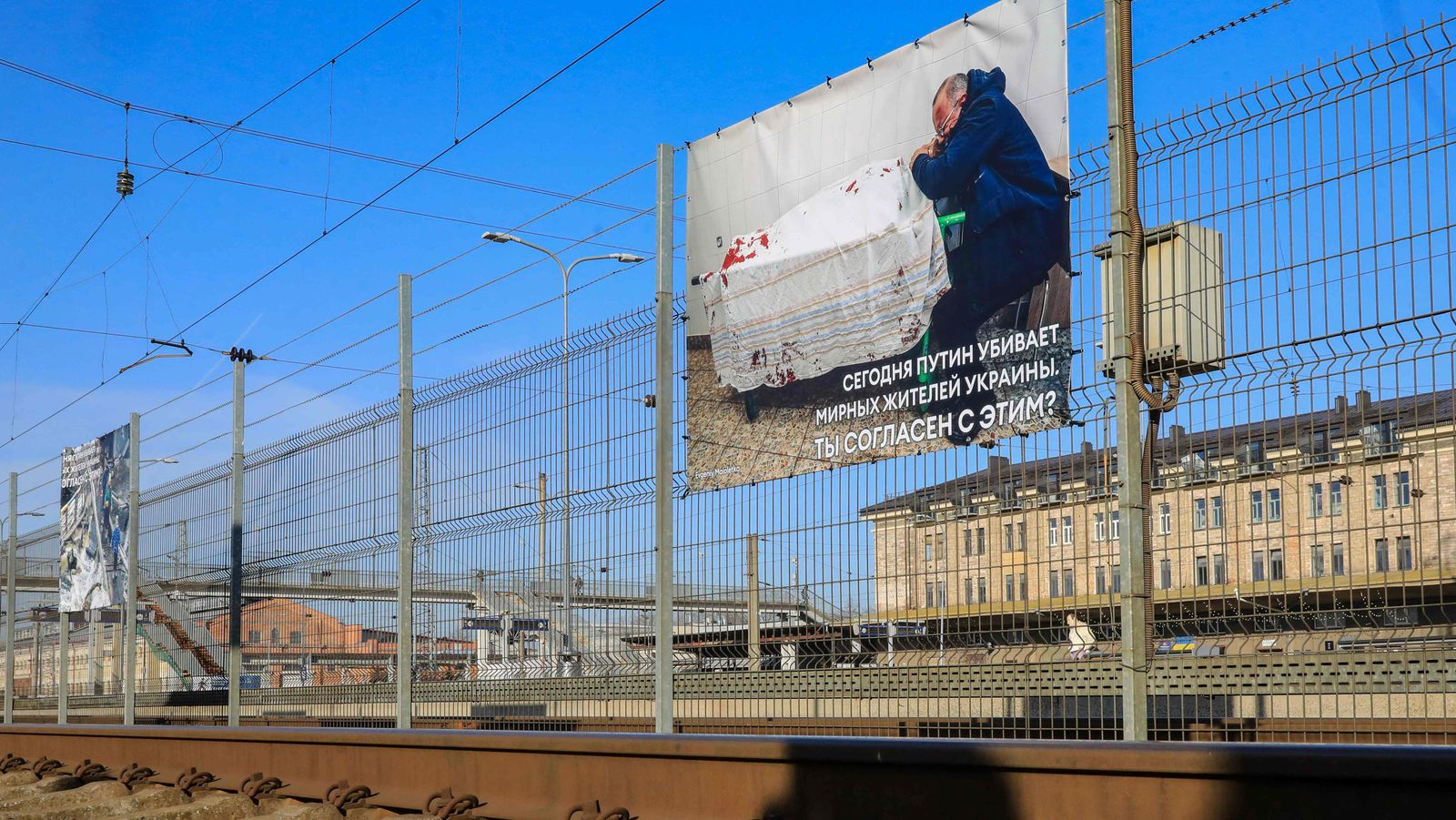 A photo of a Ukrainian man who cries over his son's lifeless body at a hospital in Mariupol, Ukraine, by Evgeniy Maloletka, a photographer working for Associated Press (AP), is seen next to other photographs of Russia's war in Ukraine at the railway station in Vilnius, Lithuania on March 25, 2022, where transit trains from Moscow to Kaliningrad make a stop over. - An exhibition of shocking images from the war in Ukraine opened on March 25 at a train station in Lithuania with the aim of giving Russian transit travellers a true picture of the conflict. The Baltic state allows 100 trains a month carrying Russian passengers to transit to and from the exclave of Kaliningrad under a special arrangement between Lithuania, the European Union and Russia. (Photo by PETRAS MALUKAS / AFP) - AFP