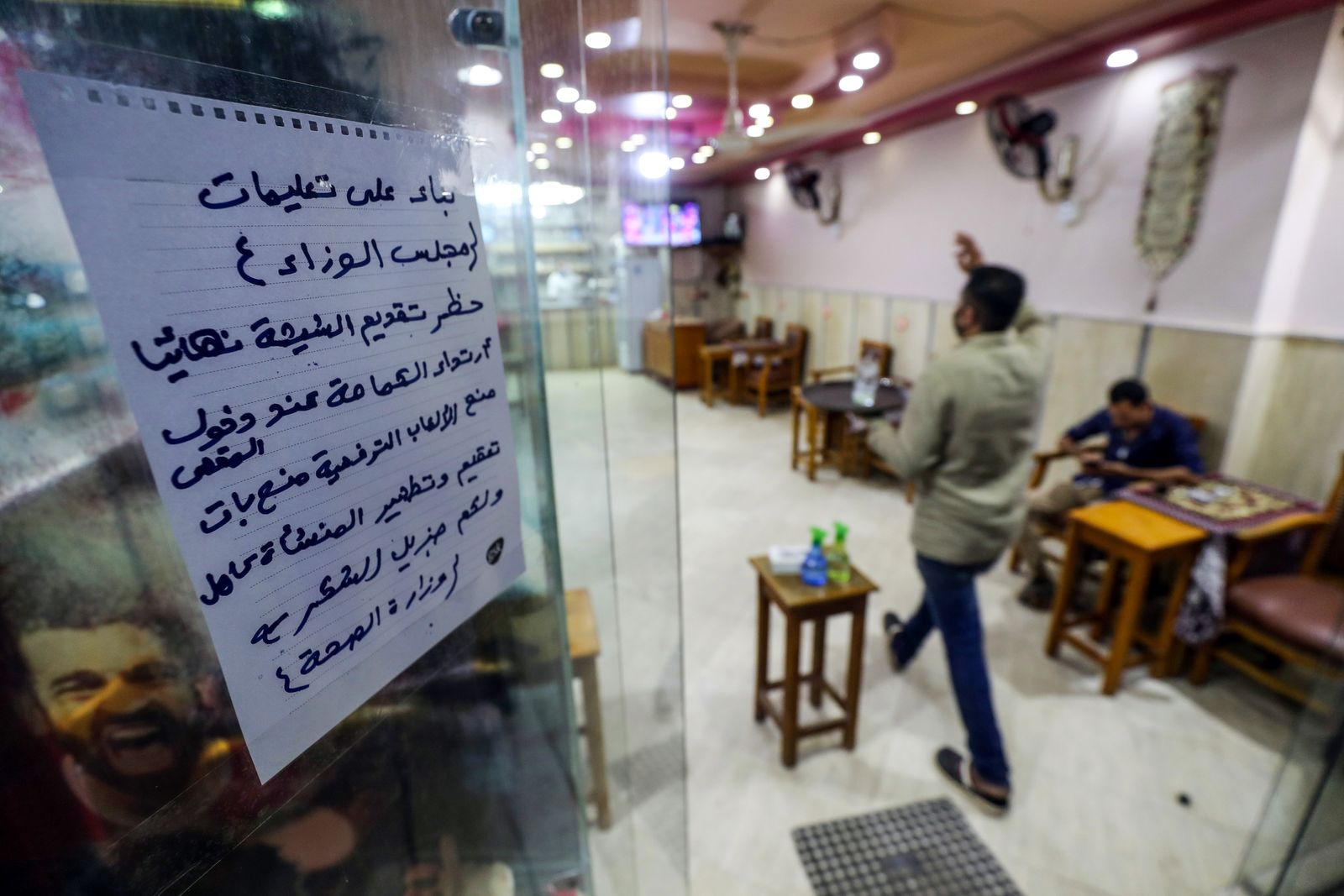لافتة تدعو الزبائن لاتباع تعليمات وزارة الصحة على باب مقهى في القاهرة  - AFP