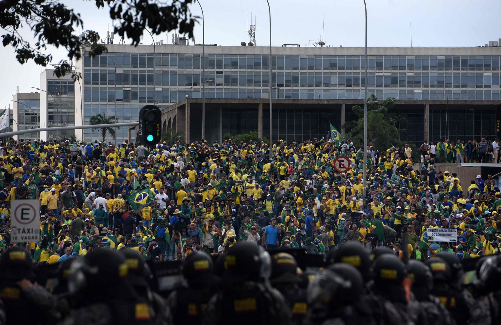 Supporters of Brazilian former President Jair Bolsonaro invading several governmental building are confronted by security forces (foreground) in Brasilia on January 8, 2023. - Hundreds of supporters of Brazil's far-right ex-president Jair Bolsonaro broke through police barricades and stormed into Congress, the presidential palace and the Supreme Court Sunday, in a dramatic protest against President Luiz Inacio Lula da Silva's inauguration last week. (Photo by Ton MOLINA / AFP) - AFP