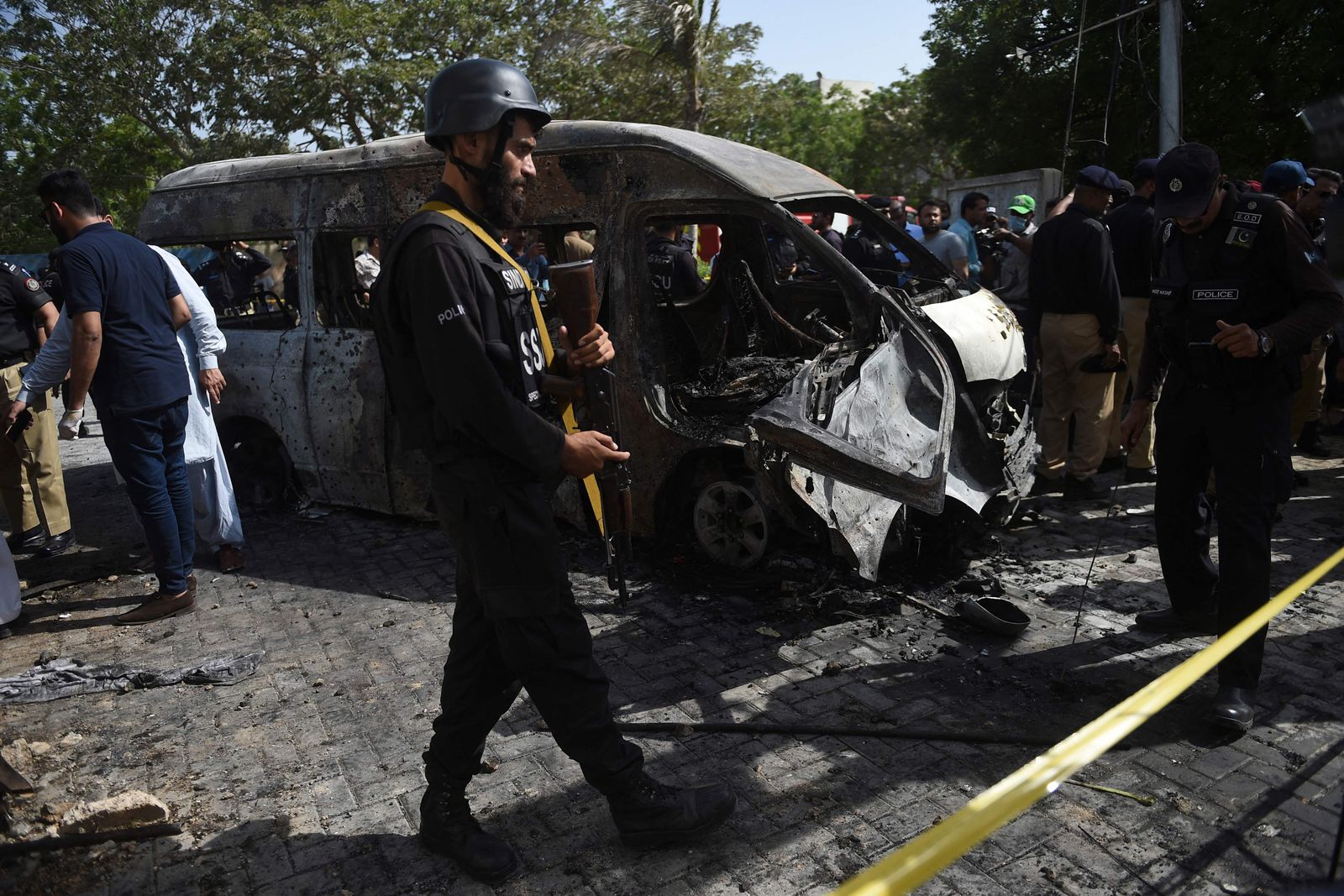 Police inspect a site around damaged vehicles following a suicide bombing near the Confucious Institute affiliated with the Karachi University, in Karachi on April 26, 2022. - A woman suicide bomber from a Pakistan separatist group killed four people, including three Chinese nationals, in an attack on a vehicle carrying staff from the Confucious Institute affiliated with the Karachi University. (Photo by Rizwan TABASSUM / AFP) - AFP