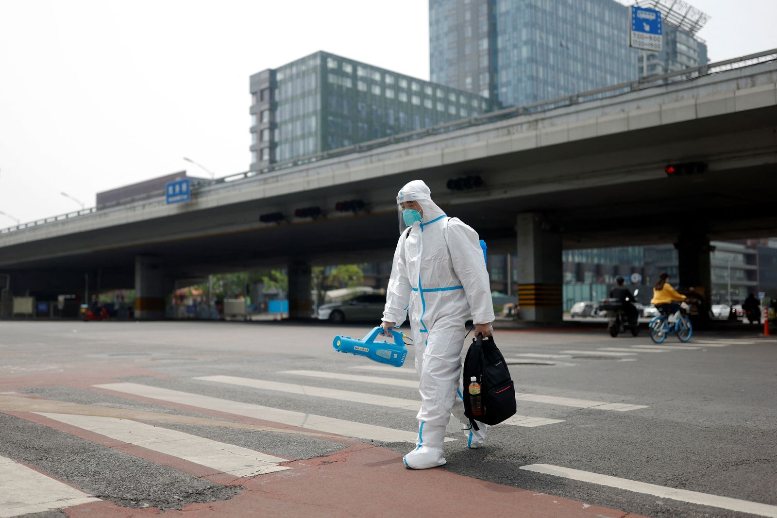 عامل صحي يحمل حقيبة ومعدات التعقيم يسير في أحد شوارع شنغهاي الخالية جراء الإغلاق. 29 أبريل 2022  - REUTERS