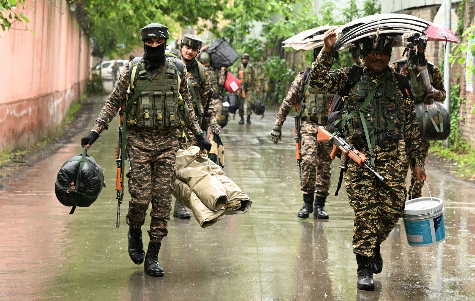 Indian security personnel walk during a rainfall as they are deployed to polling stations ahead of the fourth phase of voting of India's general elections in Srinagar on May 12, 2024. India's six-week election is set to resume on May 13 including in Kashmir, where voters are expected to show their discontent with dramatic changes in the disputed territory under Prime Minister Narendra Modi's government. (Photo by TAUSEEF MUSTAFA / AFP)