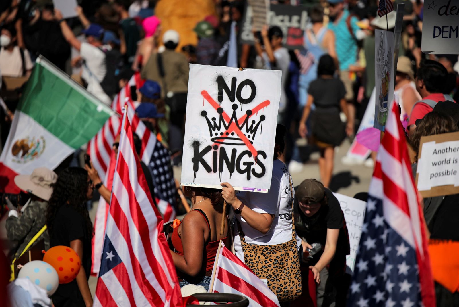 A protester holds a sign reading 'NO KINGS' with a crown illustration crossed out during a 'No Kings' protest against U.S. President Donald Trump's policies, outside City Hall in Los Angeles, California, U.S., October 18, 2025. REUTERS/Daniel Cole