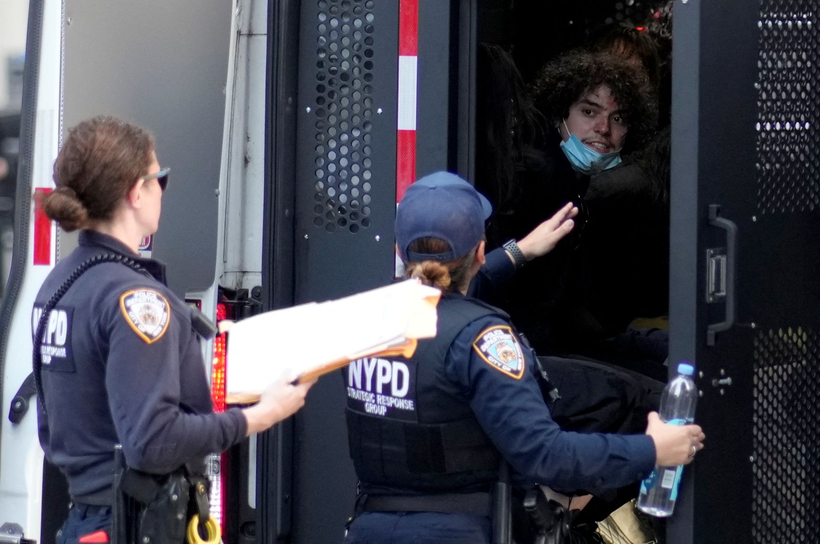 Law enforcement officers talk with detainees sitting inside a police vehicle during a protest against federal immigration sweeps near the U.S. immigration court at the Jacob K. Javits Federal Building in New York City, U.S., June 10, 2025. REUTERS/Eduardo Munoz