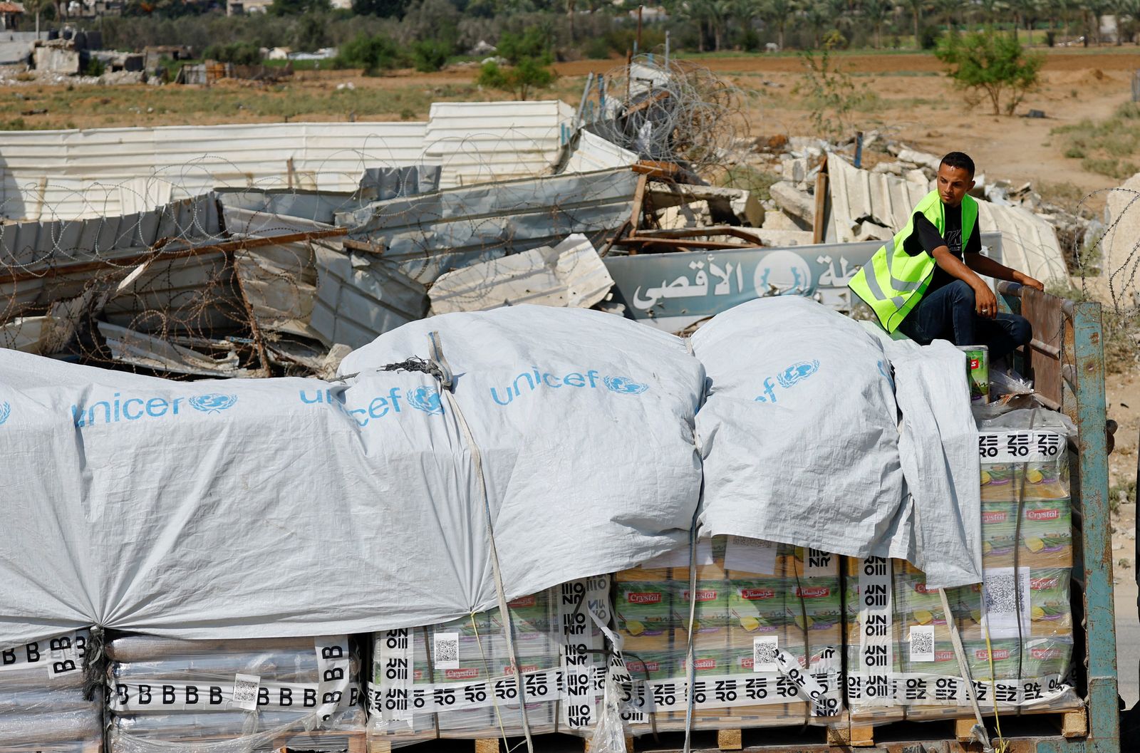 A man sits on cargo as trucks deliver aid for Palestinians, amid a ceasefire between Israel and Hamas in Gaza, in Khan Younis, in the southern Gaza Strip, October 17, 2025. REUTERS/Mahmoud Issa