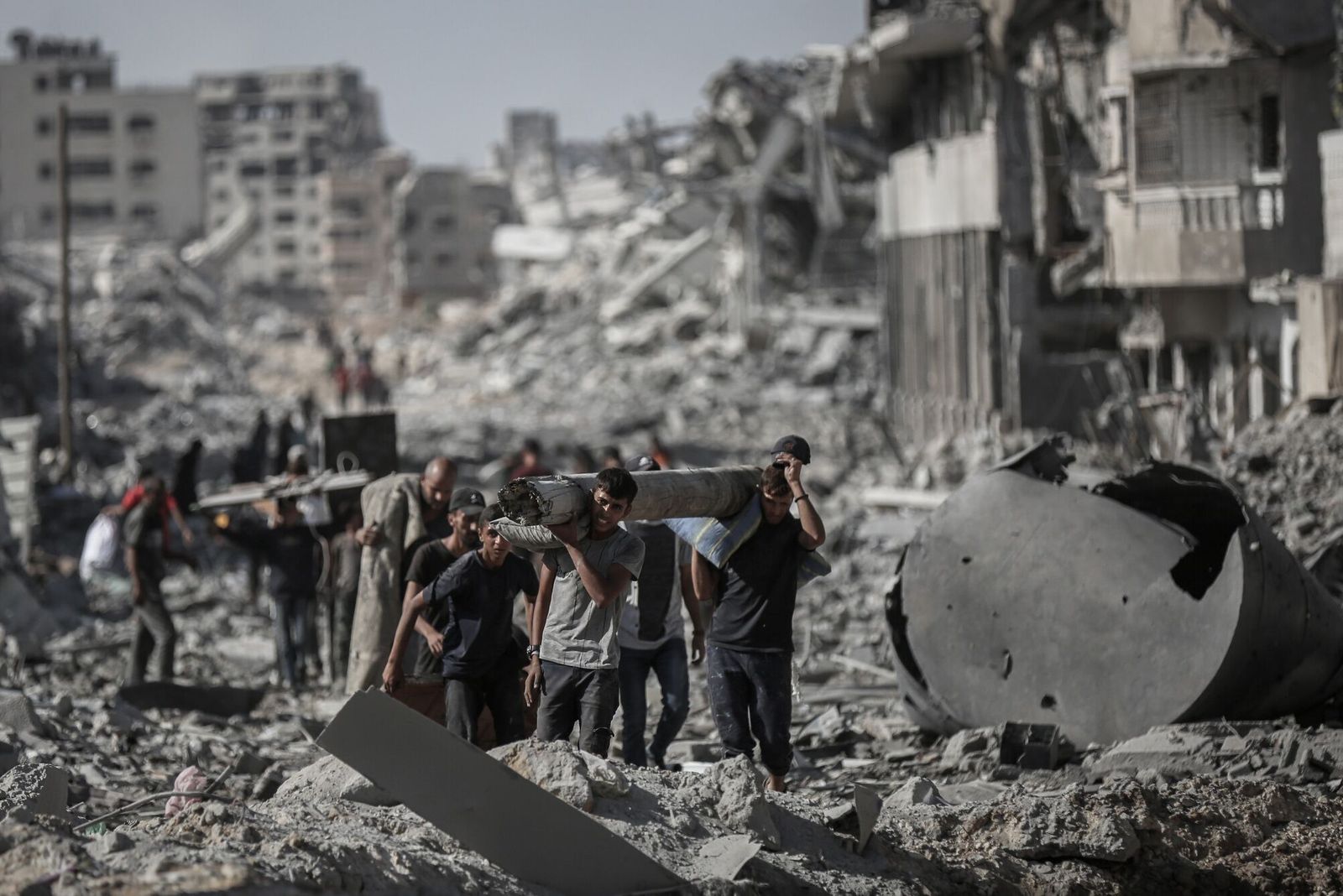 Palestinians carry a salvaged timber over rubble after the ceasefire in Gaza City, Gaza, on Friday, Oct. 10, 2025. Israel�s cabinet approved a deal that will see Hamas free all remaining hostages held in Gaza in exchange for around 2,000 prisoners, a major step toward ending a two-year war that�s killed tens of thousands of people and destabilized the wider Middle East. Photographer: Ahmad Salem/Bloomberg