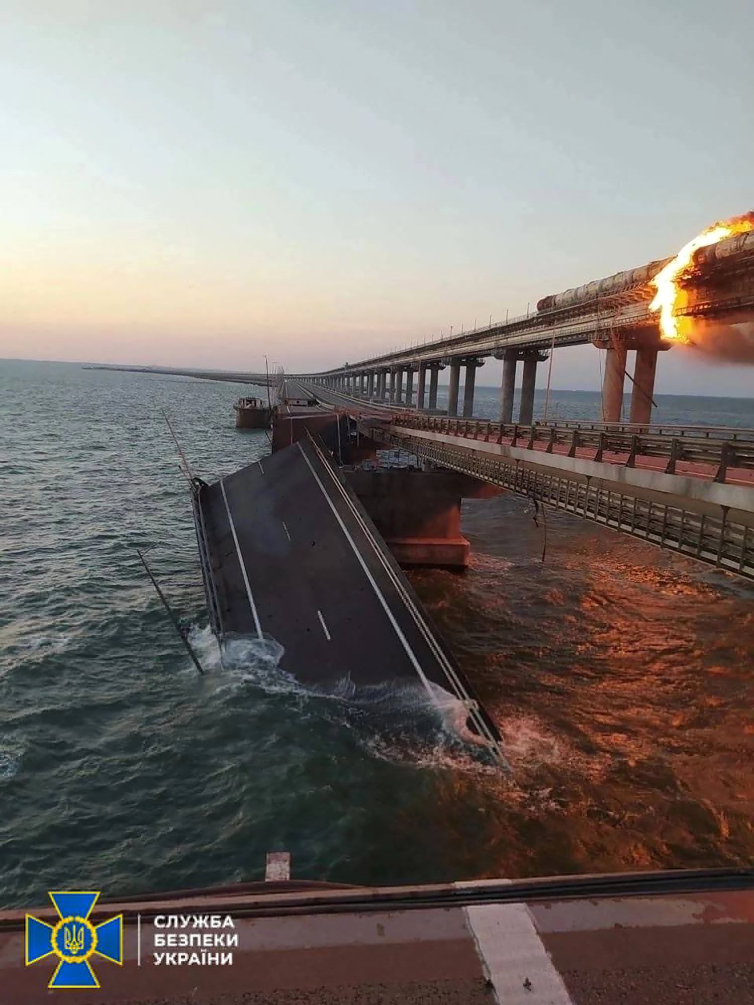 This handout picture released by Security Service of Ukraine shows a fire sparked by a car bomb that has broken out on a key bridge linking Crimea to Russia, near Kerch, on October 8, 2022. - The road-and-rail bridge, built on the orders of Russian President Vladimir Putin and inaugurated in 2018, was a key transport link for carrying military equipment to Russian soldiers fighting in Ukraine, especially in the south, as well as ferrying troops across. (Photo by SECURITY SERVICE OF UKRAINE / AFP) / RESTRICTED TO EDITORIAL USE - MANDATORY CREDIT 