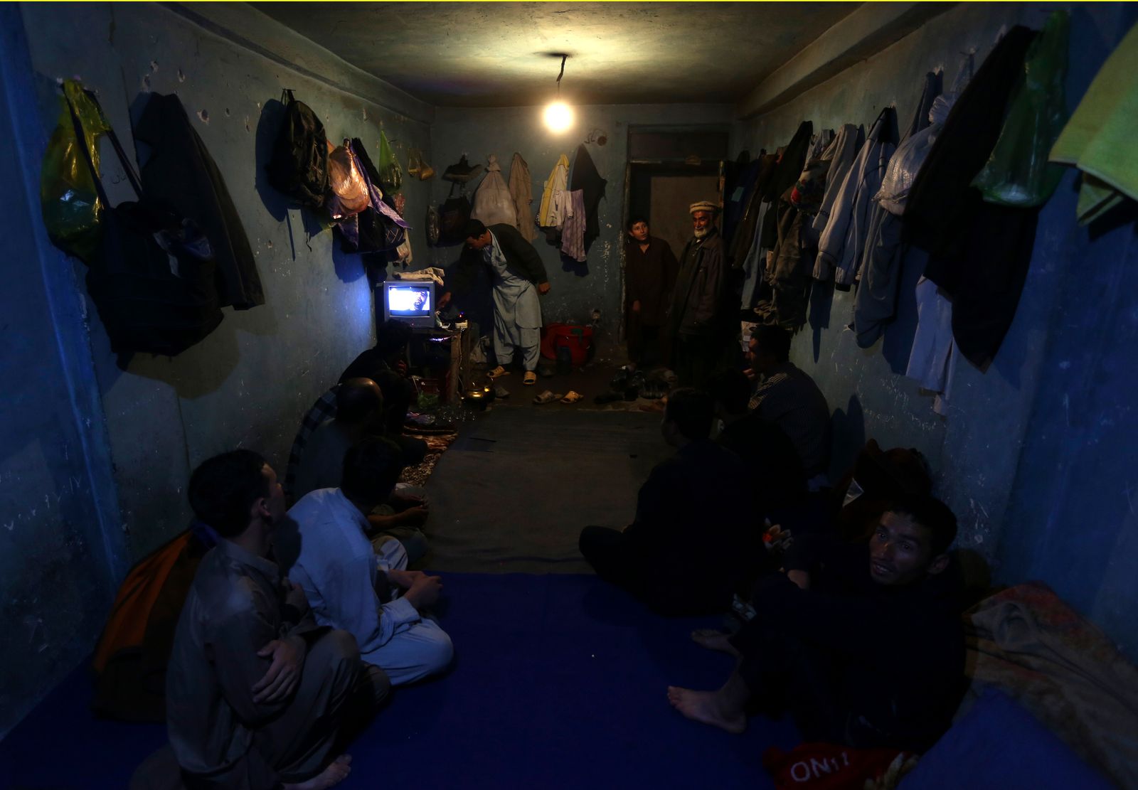 عمال أفغان يشاهدون التلفزيون في كابول مع اختصار الأنوار - 13 أبريل 2013  - REUTERS