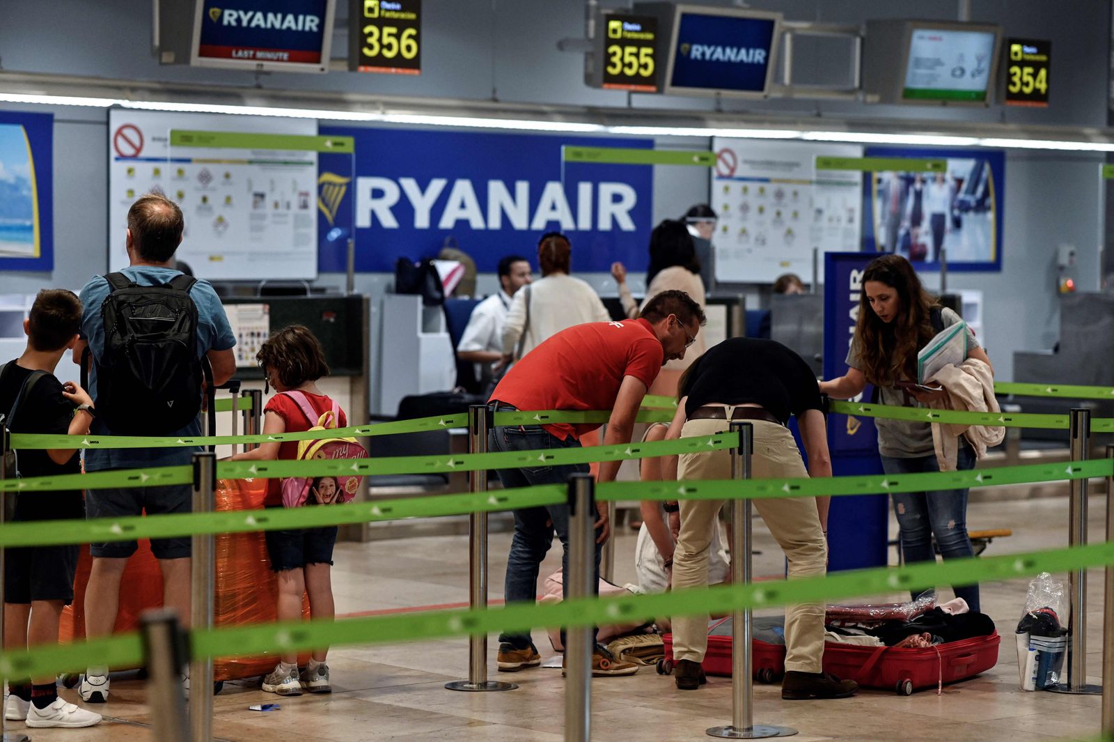 Passengers stand near the Ryanair check-in counters during a strike at Adolfo Suarez Madrid Barajas airport Madrid on June 24, 2022. - A strike by staff members at Ryanair and Brussels Airlines over pay and working conditions forced the cancelation of dozens of flights in Europe at the start of the peak summer travel season. In Spain, where Ryanair employs 1,900 people, no flights were cancelled except those heading to Belgium. (Photo by OSCAR DEL POZO / AFP) - AFP