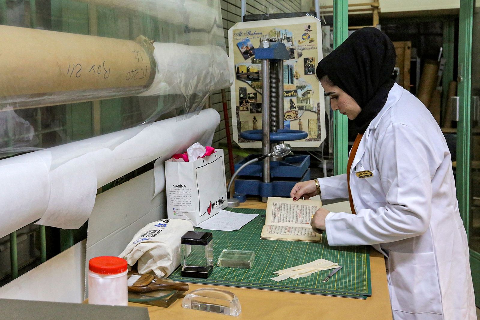 A conservator opens a manuscript undergoing restoration at the Iraqi Manuscript House's resoration lab in Iraq's capital Baghdad on December 6, 2022. - A curator in Baghdad pores over a 17th-century Persian manuscript, inside an annex of Iraq's national museum where she patiently undertakes delicate restoration work on the religious text. It is part of an enormous challenge Iraq has set itself -- preserving and digitising 47,000 of its ancient manuscripts and books. (Photo by Sabah ARAR / AFP) - AFP