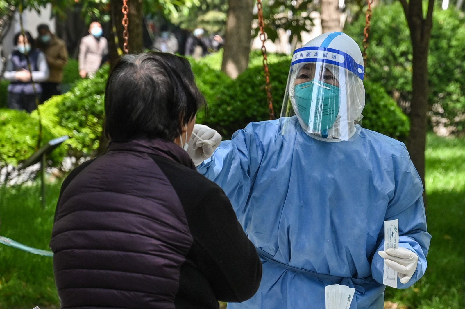 عاملة صحية تأخذ مسحة لفيروس كورونا في مجمع سكني خلال المرحلة الثانية من الإغلاق في إحدى مناطق شنغهاي. 6 أبريل 2022 - AFP