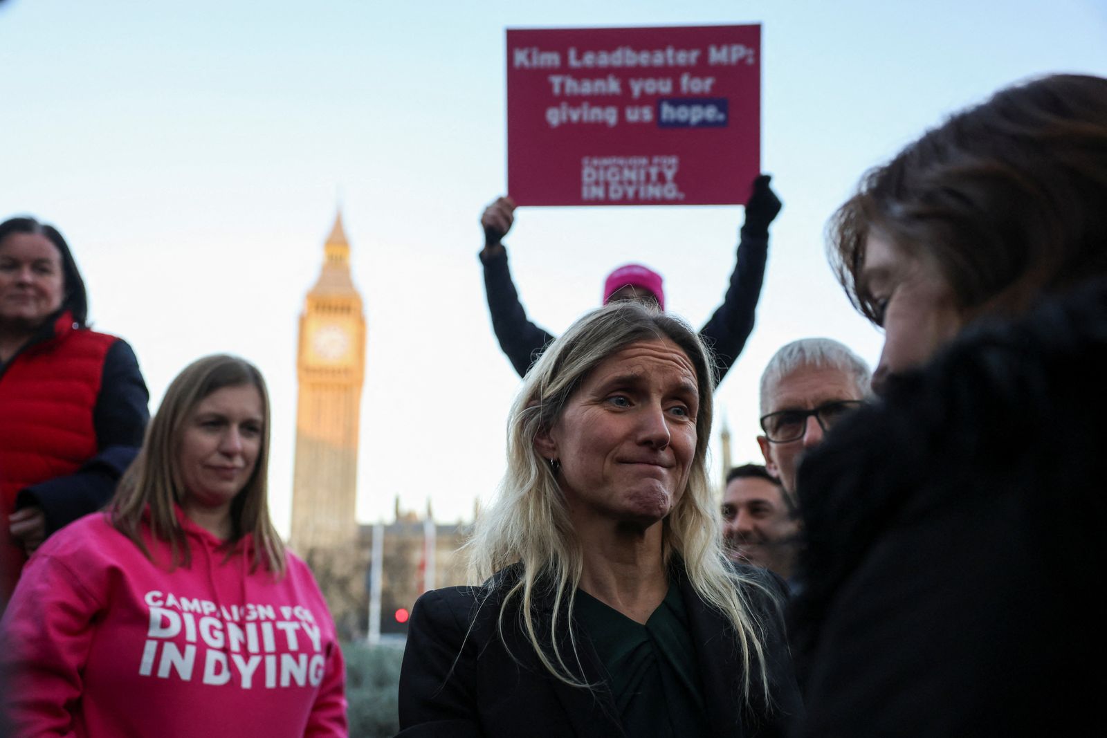 A person holds a placard as Kim Leadbeater, MP for Spen Valley, speaks to a woman, on the day of a demonstration in support of assisted dying outside the British parliament after lawmakers voted in favour of the assisted dying law, in London, Britain, November 29, 2024. REUTERS/Mina Kim