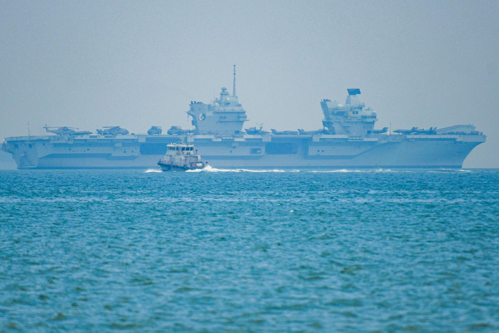 A boat passes in front of HMS Queen Elizabeth of Britain's Carrier Strike Group in Singapore on October 12, 2021. (Photo by Roslan RAHMAN / AFP) - AFP