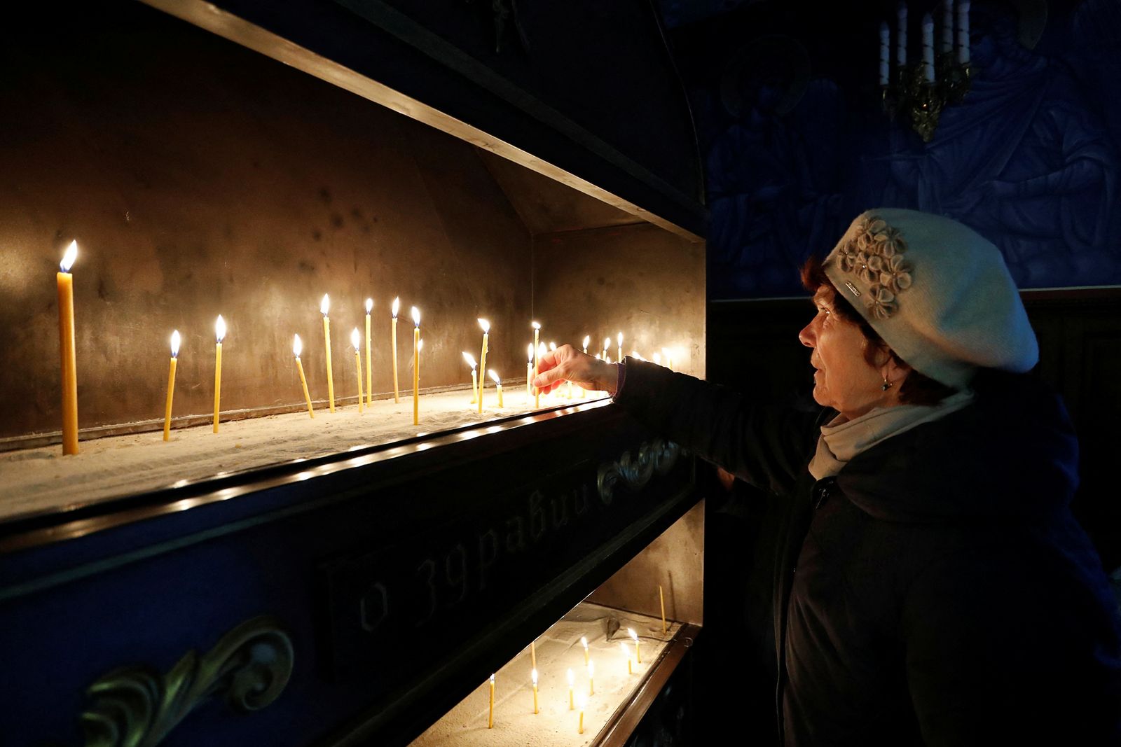 أوكرانية تنير شمعة في  قداس عيد الفصح داخل كنيسة في مدينة ماريوبل الأوكرانية. 24 أبريل 2022 - REUTERS