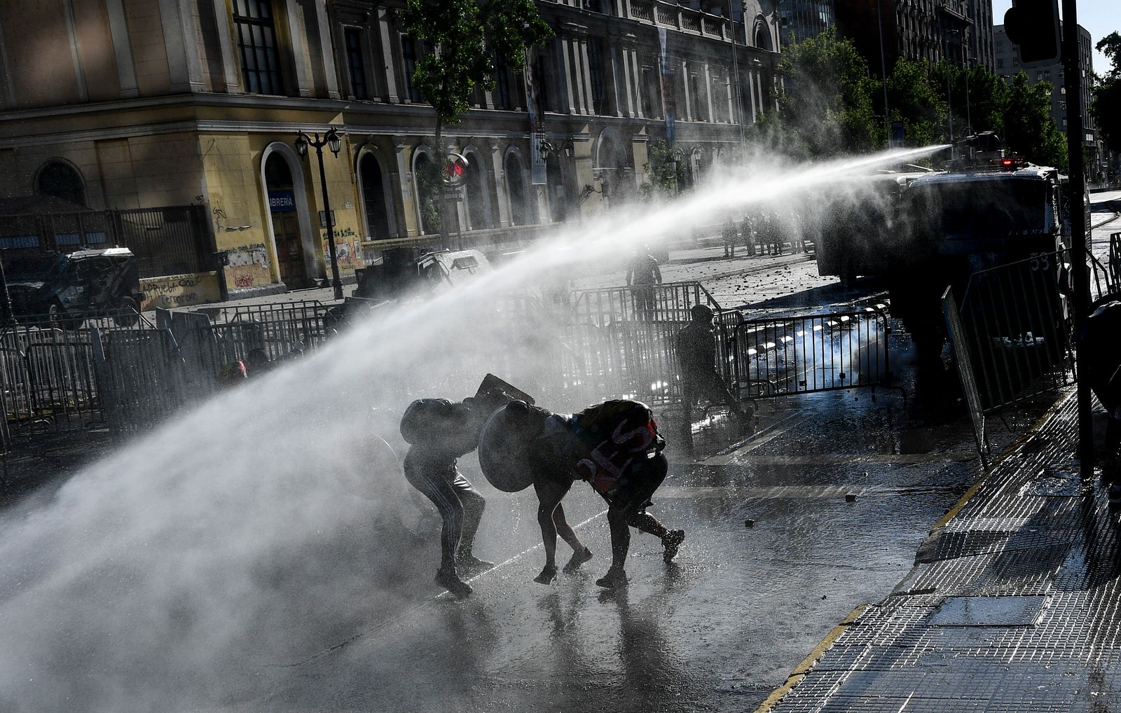 أثناء رش الشرطة التشيلية المياه على المتظاهرين خلال مواجهات بعد احتجاج على حكومة الرئيس التشيلي في سانتياغو - AFP
