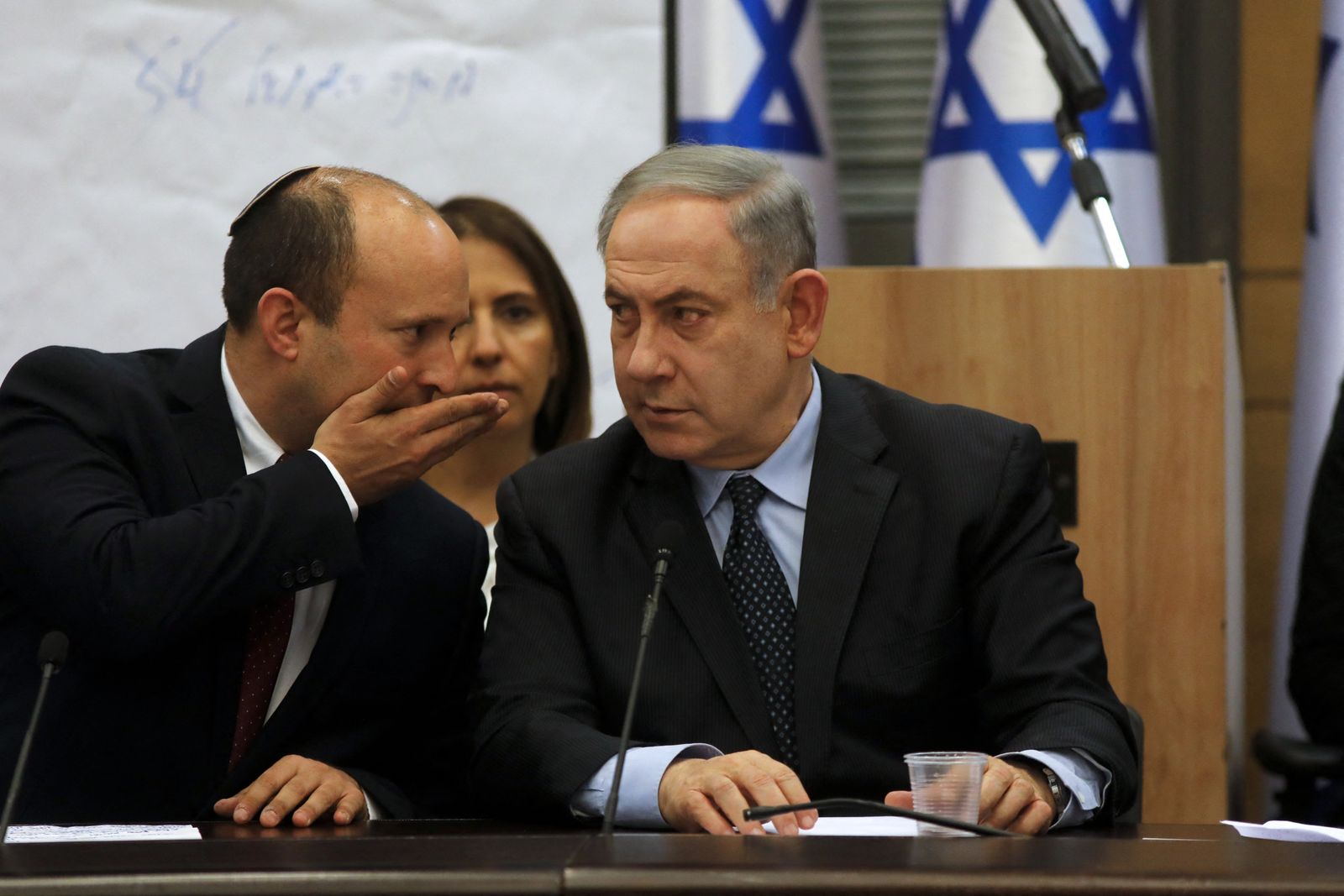 وزير الدفاع الإسرائيلي السابق نفتالي بينيت يهمس في أذن رئيس الوزراء بنيامين نتنياهو خلال اجتماع في الكنيست - 4 مارس 2020 - AFP