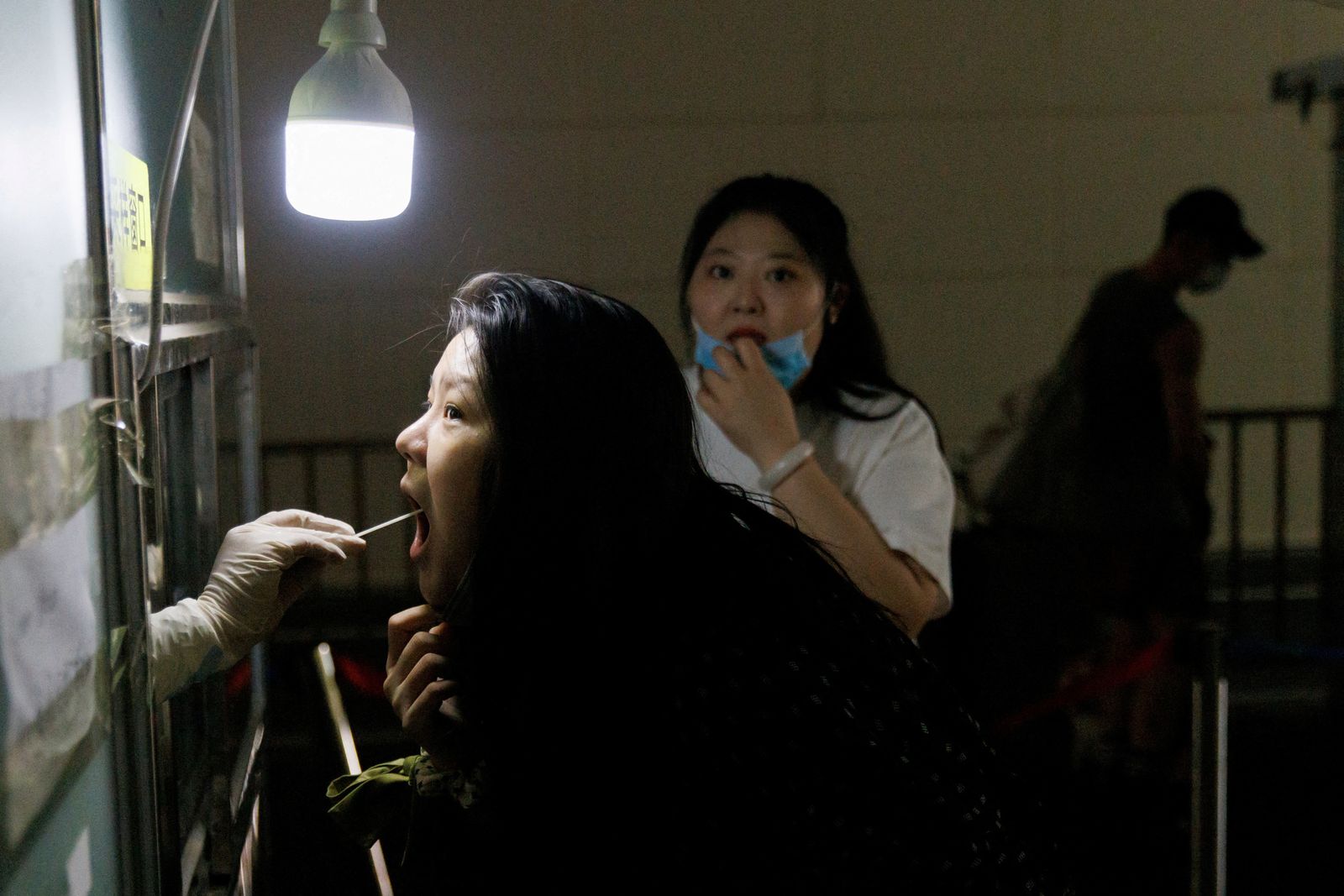 FILE PHOTO: A woman gets a swab test at a nucleic acid testing station, following a coronavirus disease (COVID-19) outbreak, in Beijing - REUTERS