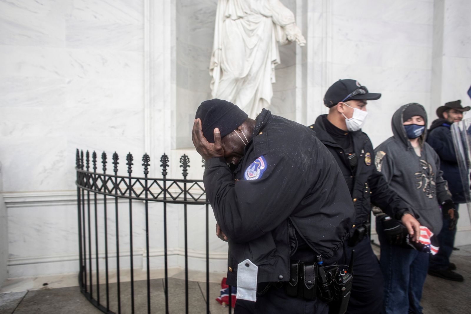 أحد أفراد شرطة الكابيتول يغطي وجهه بينما يقتحم المتظاهرون المبنى. - REUTERS