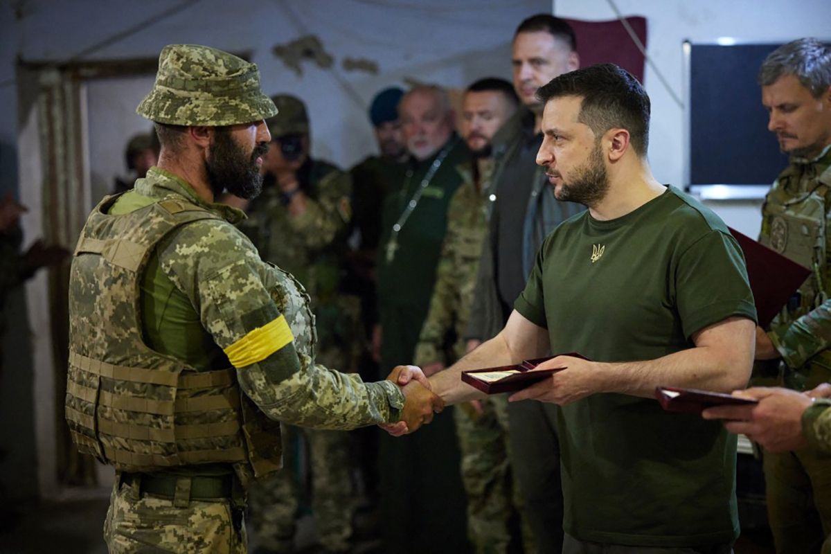 This handout picture taken and released by the press service of the Ukrainian Presidency on 18 June, 2022 shows Ukrainian President Volodymyr Zelensky (R) awarding a serviceman during his visit to the position of Ukrainian troops in Mykolaiv region. (Photo by Handout / UKRAINE PRESIDENCY / AFP) / RESTRICTED TO EDITORIAL USE - MANDATORY CREDIT 
