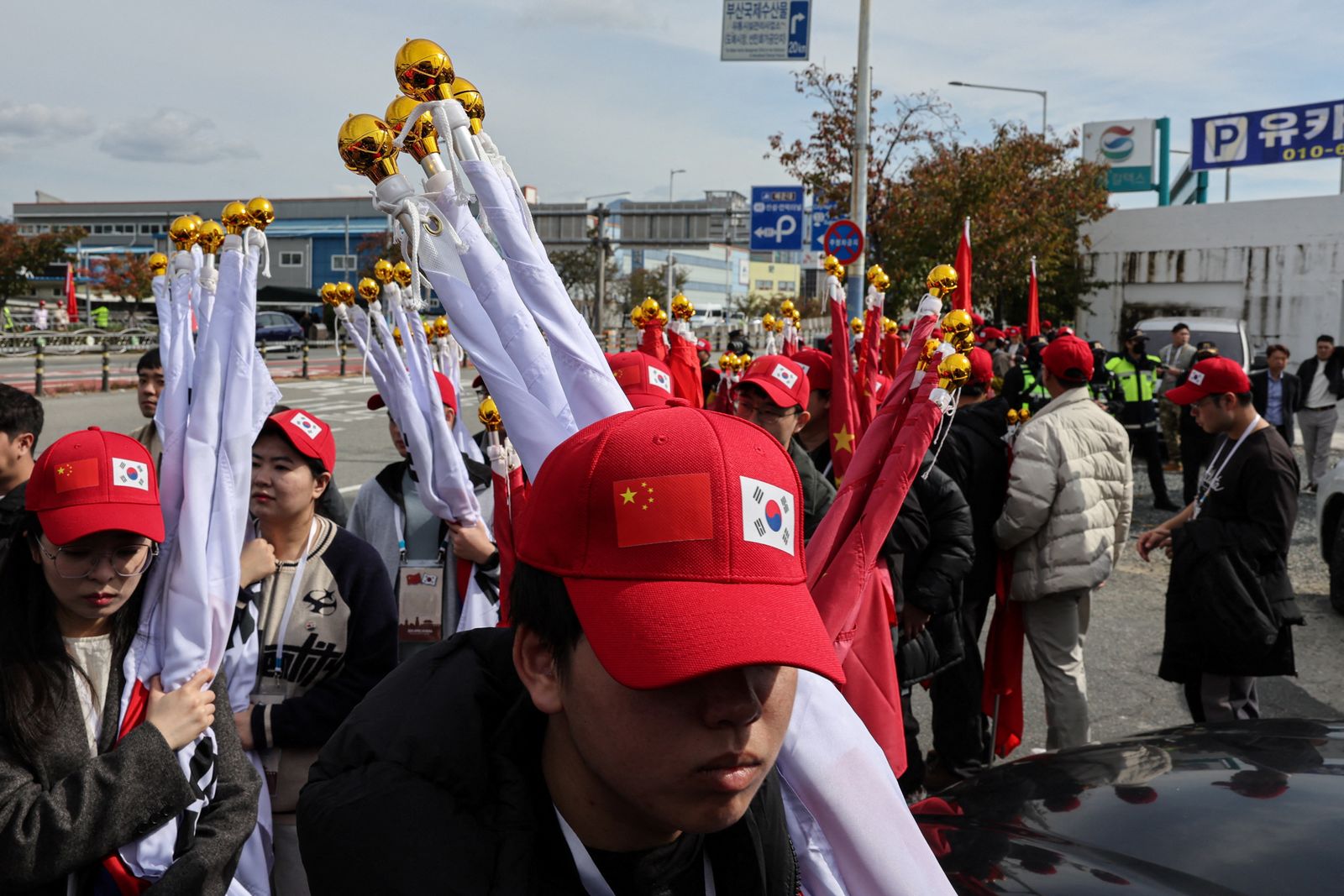 Pro-China supporters hold rolled up flags of China and South Korea  as they walk near Gimhae International Airport on the day of a bilateral meeting between U.S. President Donald Trump and Chinese President Xi Jinping on trade tensions and bilateral relations, on the sidelines of the Asia-Pacific Economic Cooperation (APEC) Summit, in Busan, South Korea, October 30, 2025. REUTERS/Tyrone Siu