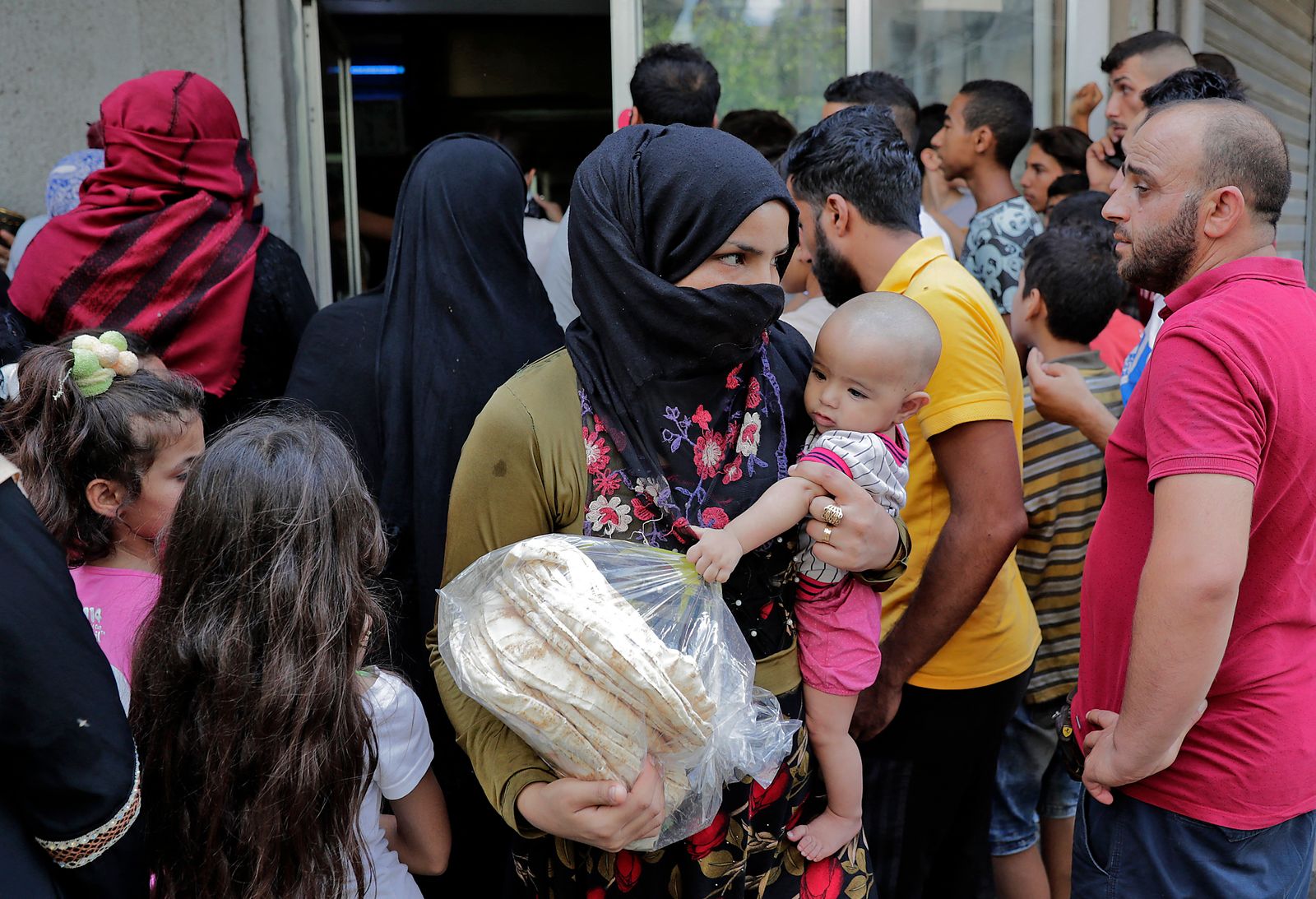  امرأة تحمل رضيعاً وحزمة خبر في حي النبعة ببيروت 13 أغسطس 2021 - AFP