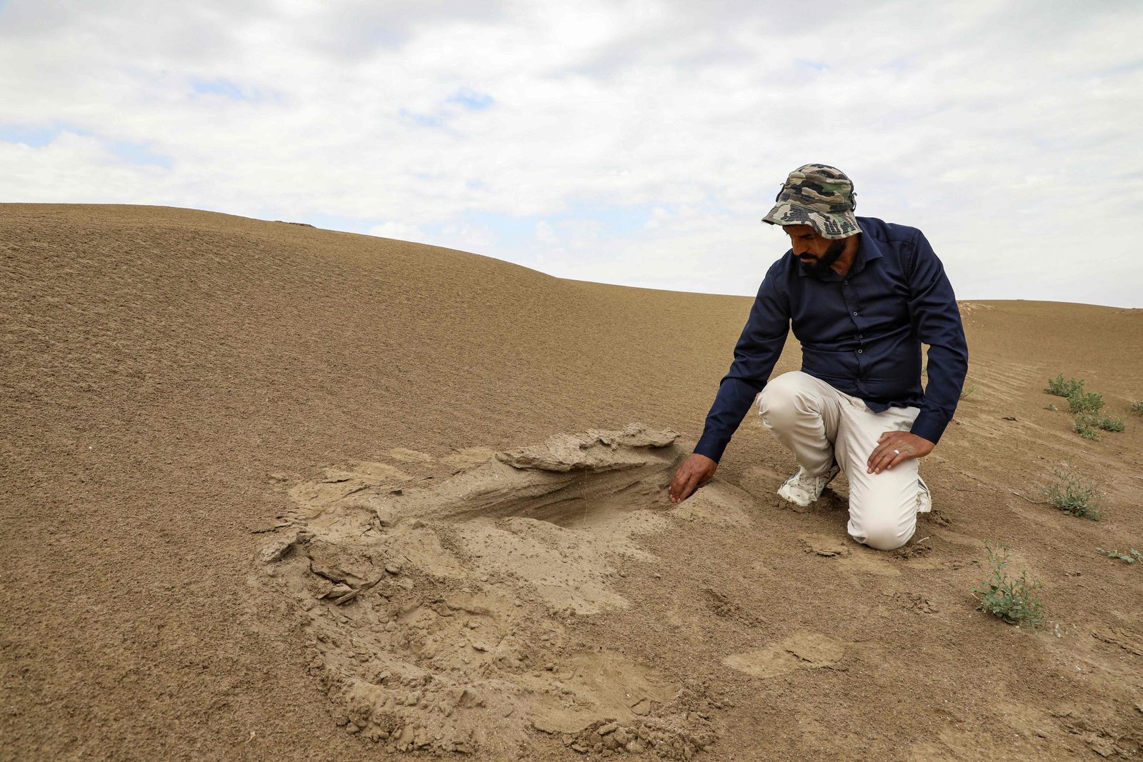 In this picture taken on March 31, 2023, archaeologist Aqeel Mansarawi searches for the remains of an ancient structure at the Umm al-Aqarib archaeological site, frequently buried by sandstorms due to desertification, in the district of al-Rifai in Iraq's southern Dhi Qar province. - Iraqi archeological marvels that survived millennia and the ravages of war now face a modern threat: being blasted and buried by sandstorms linked to climate change. Many Babylonian treasures, painstakingly unearthed, are slowly disappearing again under wind-blown sand in a land parched by rising heat and prolonged droughts. (Photo by Asaad NIAZI / AFP) - AFP