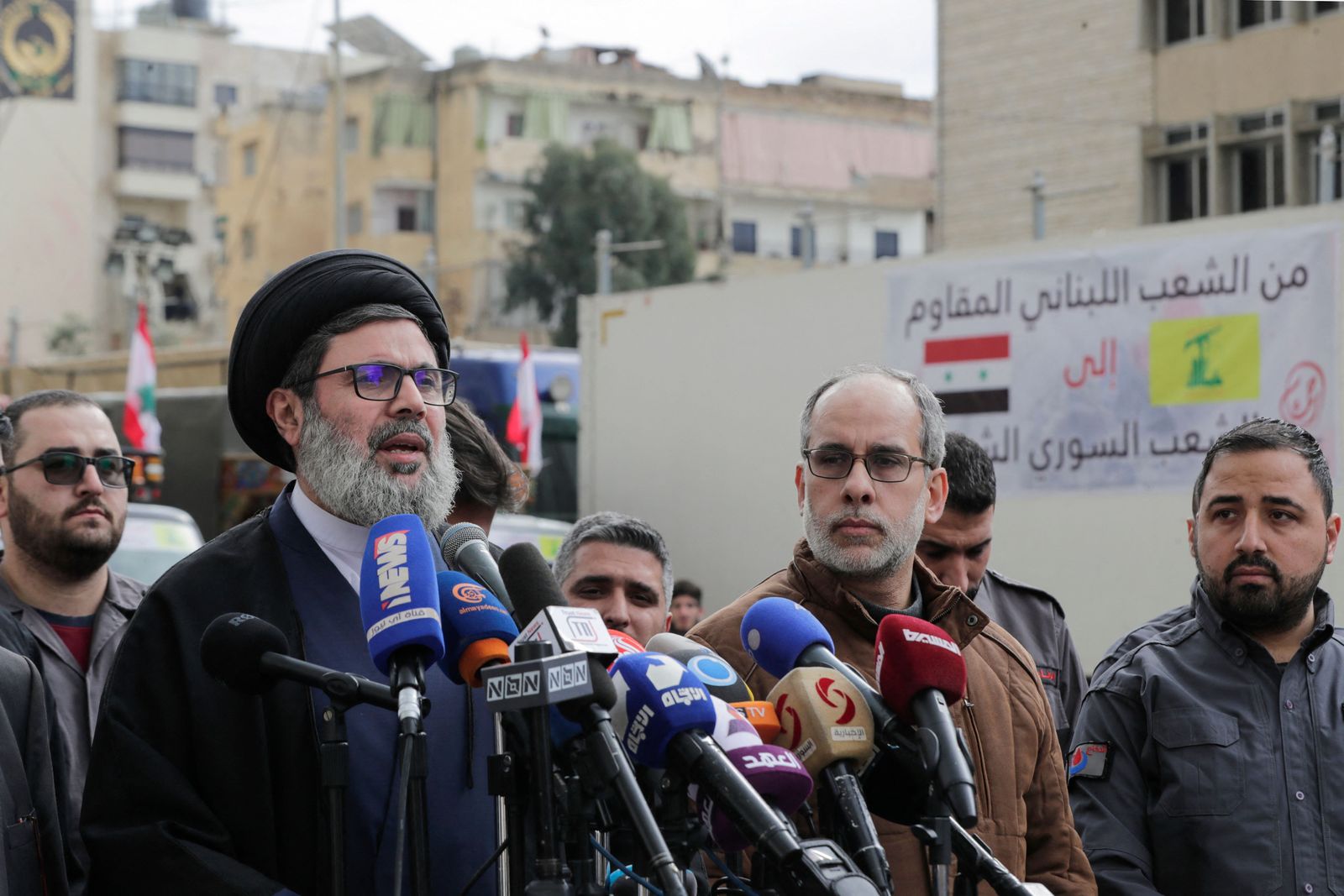 Head of Hezbollah's Executive Council Hashem Safieddine (L) speaks as trucks loaded with humanitarian aid provided by the Lebanese Shiite group set out for Syria from the Lebanese capital's southern suburb on February 12, 2023, in the aftermath of a deadly earthquake. (Photo by ANWAR AMRO / AFP)