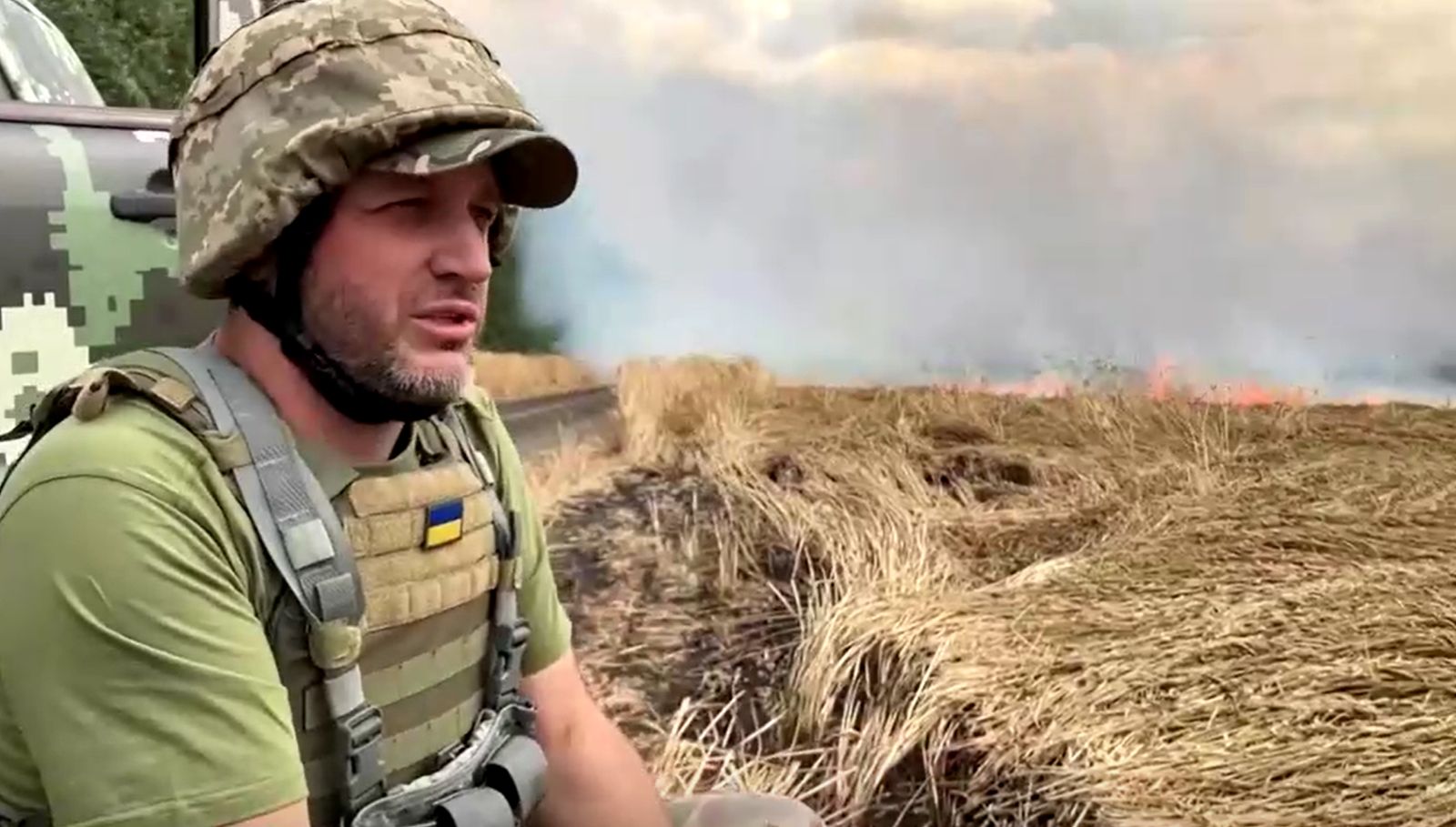 الجندي دميترو يجلس أمام حقل يحترق في منطقة زابوريزجيا بأوكرانيا - 18 يوليو 2022 - REUTERS