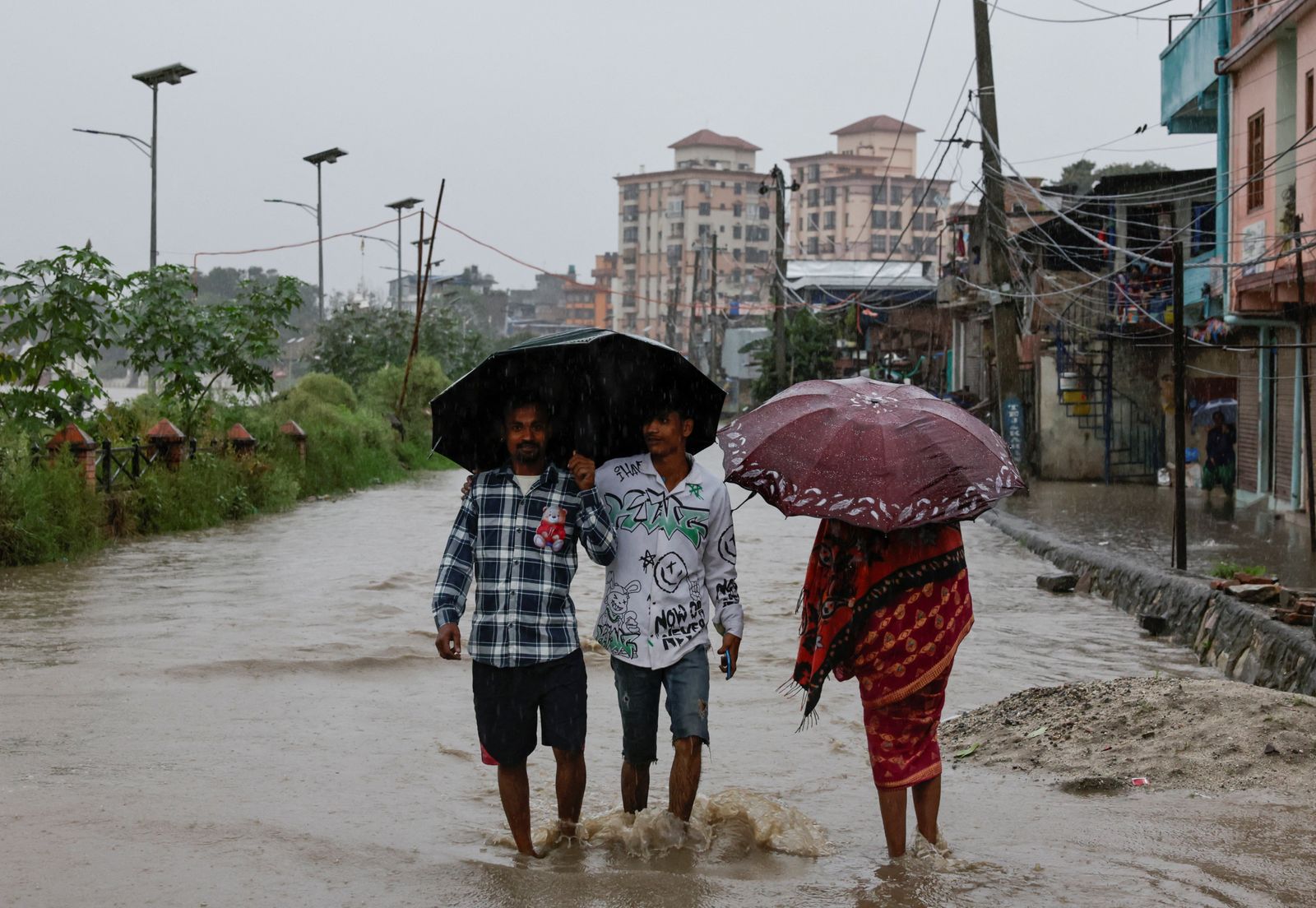 People wade through a flooded street along the bank of overflowing Bagmati River following heavy rains, in Kathmandu, Nepal, October 4, 2025. REUTERS/Navesh Chitrakar