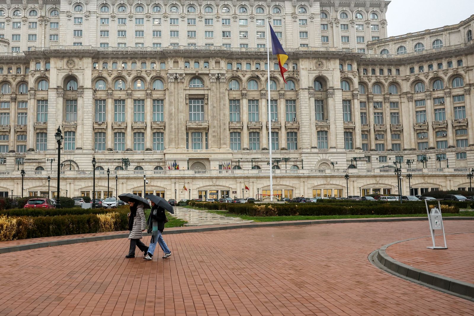 People walk past the Palace of the Parliament, ahead of the runoff for the presidential elections in Bucharest, Romania, December 6, 2024.  REUTERS/Louisa Gouliamaki