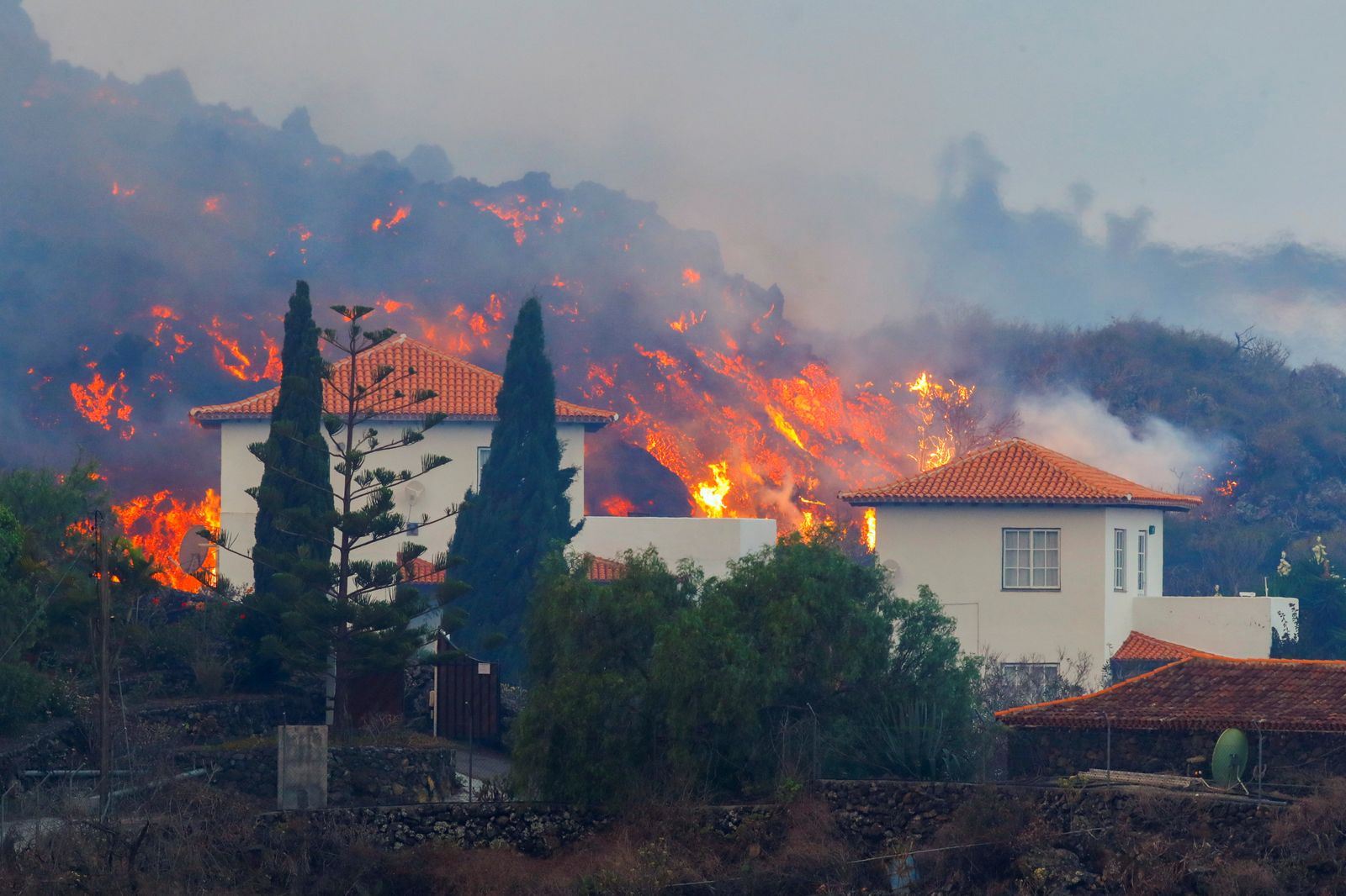 Lava flows behind a house following the eruption of a volcano in Spain - REUTERS