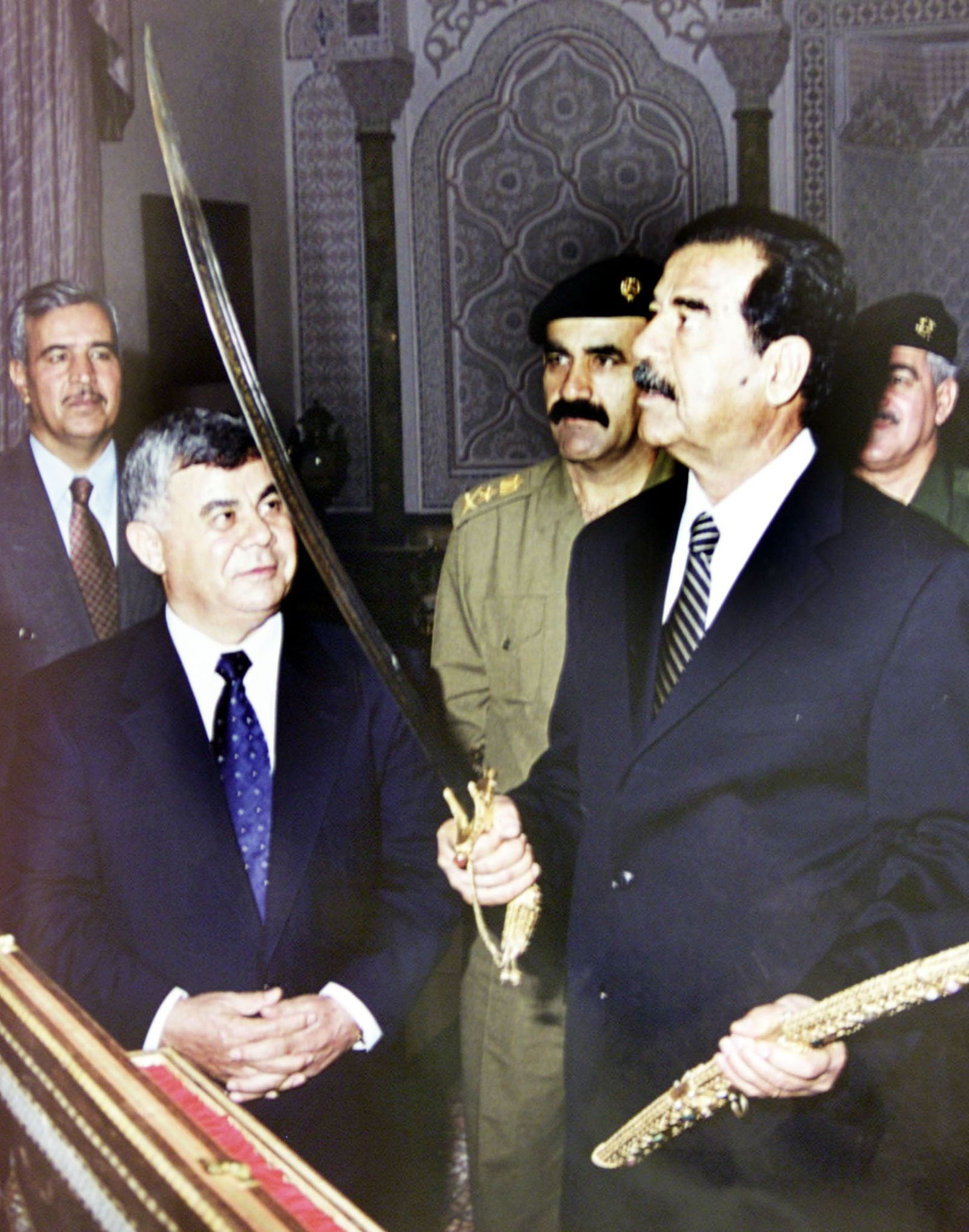 الرئيس العراقي السابق صدام حسين يستعرض سيفاً قدمه له رئيس الوزراء السوري السابق مصطفى ميرو (إلى اليسار) وذلك خلال زيارة للأخير إلى بغداد لتعزيز العلاقات الدبلوماسية بعد نحو عقدين من القطيعة 13 أغسطس 2001 - REUTERS