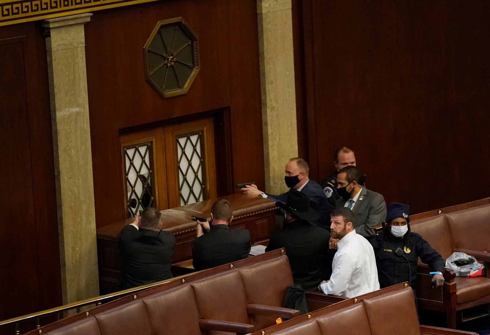 عناصر أمن من شرطة الكونغرس سشهرون أسلحتهم مع محاولات المتظاهرين اقتحام قاعة مجلس النواب في الكونغرس - AFP