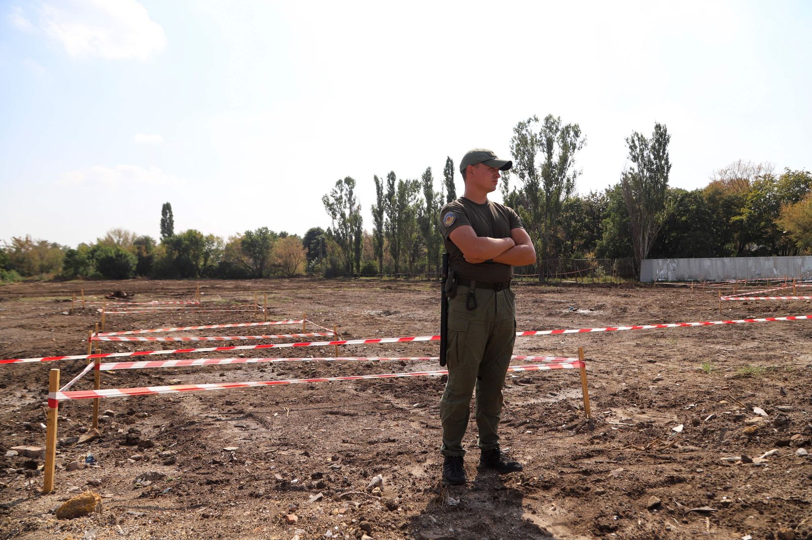 A security person stands guard at the mass graves site discovered on an abandoned area near the city airport where until recently was a dump in Odessa on August 30, 2021. - The remains of thousands of people believed to be victims of Stalin's Terror have been discovered in Ukraine's southern city of Odessa, local authorities said on August 30, 2021. The bones of between 5,000 to 8,000 people were found in over two dozen graves close to Odessa's airport, making it one of the largest mass graves unearthed in Ukraine so far. (Photo by Oleksandr GIMANOV / AFP) - AFP