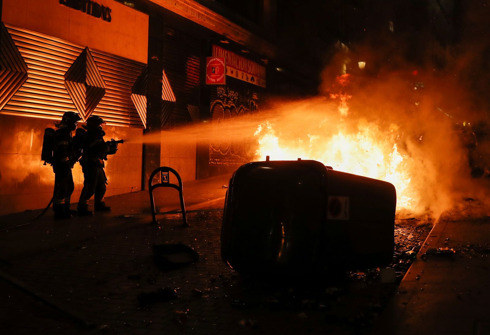 عناصر من الدفاع المدني الإسباني خلال محاولة إخماد حريق نشب خلال مظاهرات عنيفة في إقليم كتالونيا احتجاجاً على اعتقال مغني راب - REUTERS