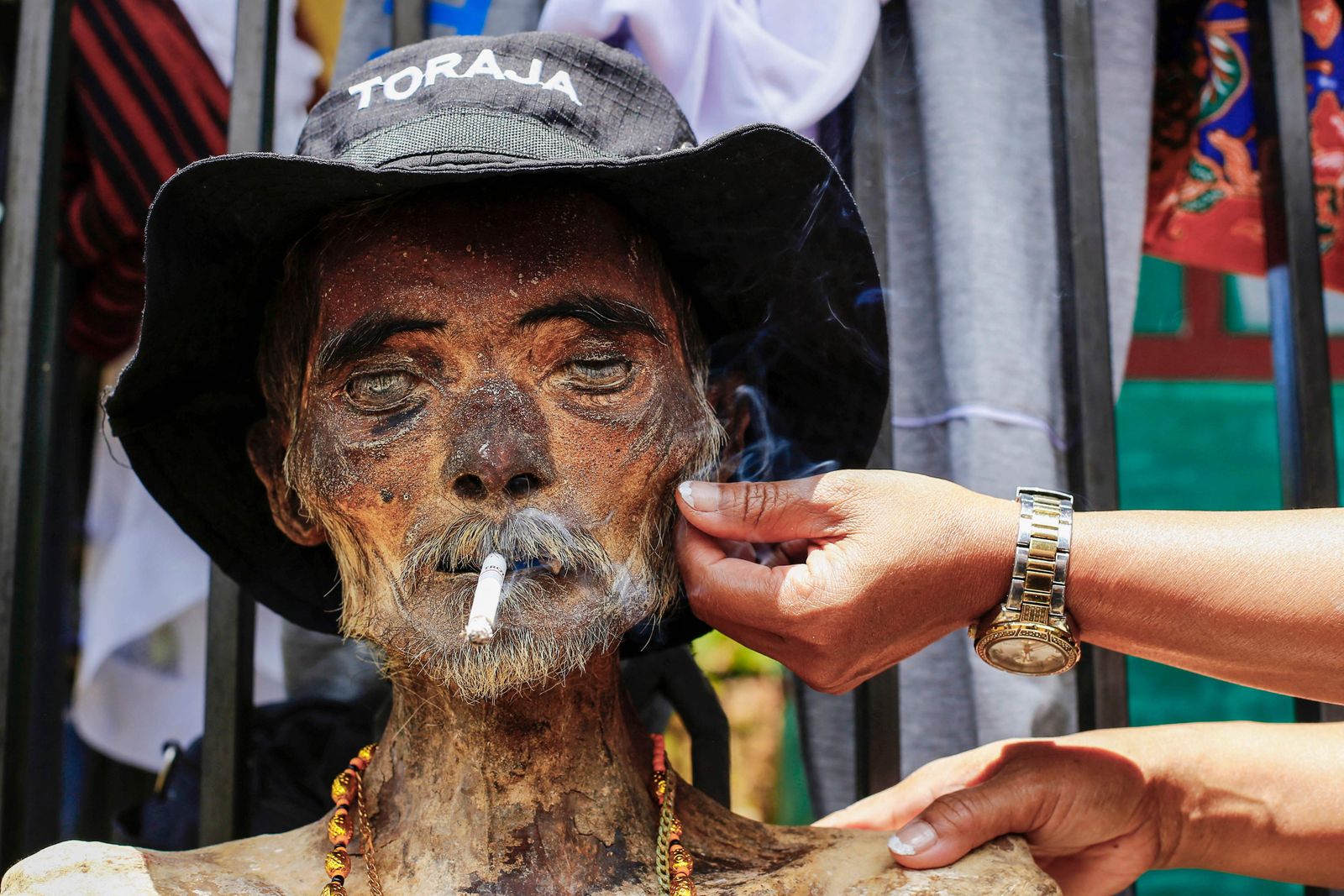 Family members perform the Manene traditional rite, cleaning the relatives' preserved remains, in Lembang on August 15, 2022, which is held every three years in August and is said to bless the harvest of rice fields. (Photo by ANDRI SAPUTRA / AFP) - AFP