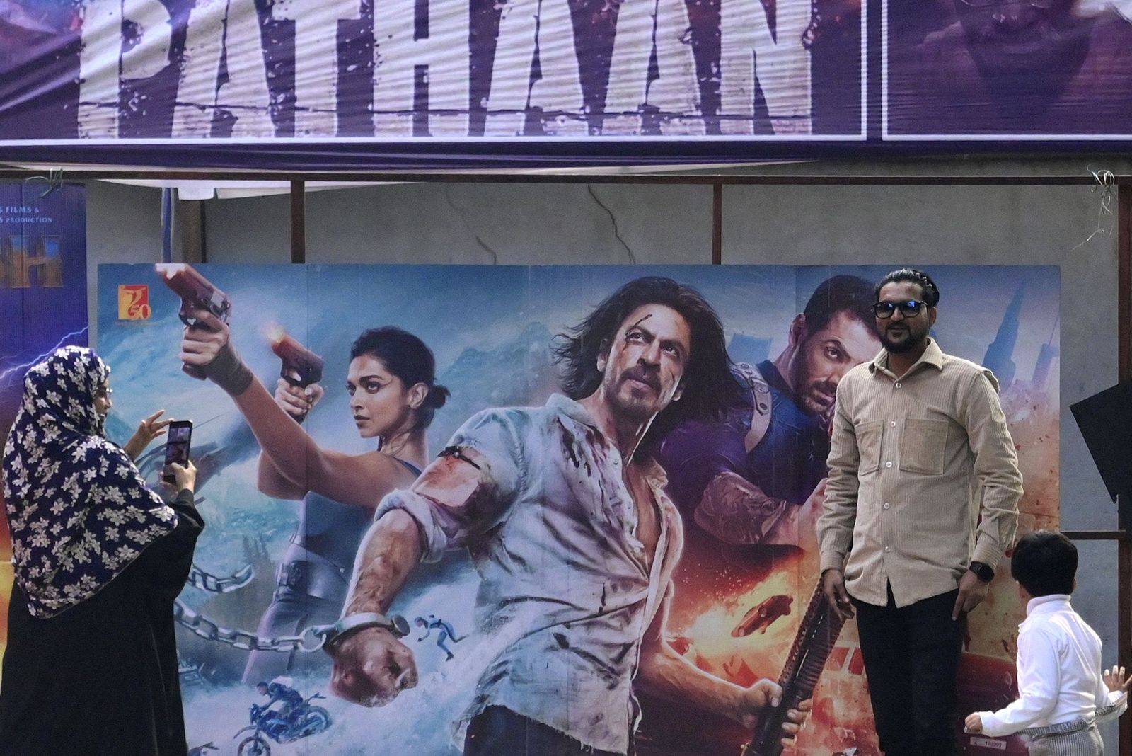 Moviegoers pose for pictures in front of a poster of the Bollywood movie 'Pathaan' outside a cinema hall in Prayagraj on January 25, 2023. - Bollywood megastar Shah Rukh Khan returned to the silver screen on January 25 for the first time in four years with an action-packed rollercoaster film that has sparked ire from Hindu right-wingers. (Photo by SANJAY KANOJIA / AFP) - AFP