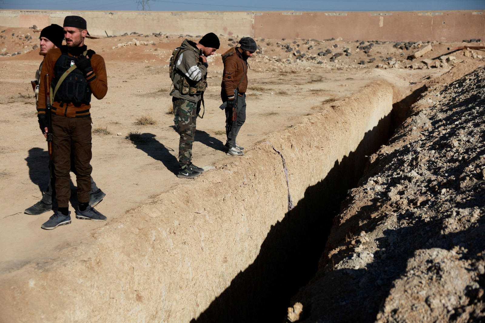 Fighters of the ruling Syrian body inspect the site of a mass grave from the rule of Syria's Bashar al-Assad, according to residents, after the ousting of al-Assad, in Najha, Syria, December 17, 2024. REUTERS/Ammar Awad TPX IMAGES OF THE DAY