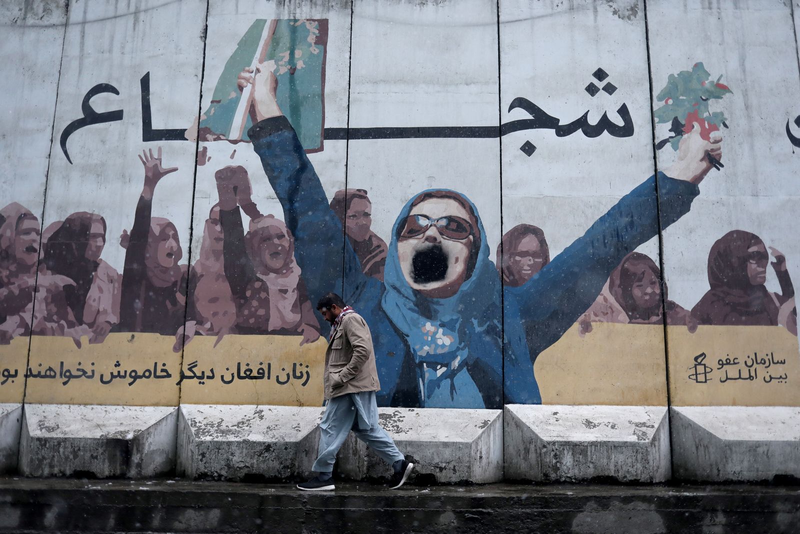 A man walks past a painting on the wall of the former embassy for women's affairs in Kabul - REUTERS