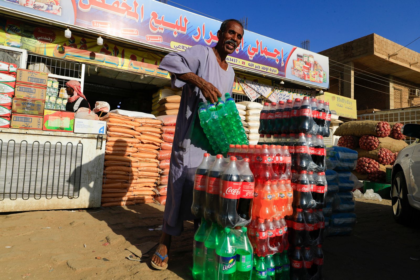 سوداني يرتب عبوات المشروبات الغازية أمام محل لبيع المواد الغذائية بالخرطوم. 19 يناير 2023 - AFP