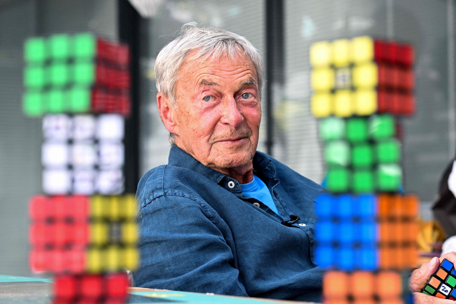 Hungarian inventor Erno Rubik sits next to several Rubik's Cubes during an interview with AFP in Budapest on April 29, 2024. It was a spring day in 1974 when Hungarian architecture professor Erno Rubik created the first prototype of a movable cube made out of small wooden blocks and held together by a unique mechanism. (Photo by ATTILA KISBENEDEK / AFP)