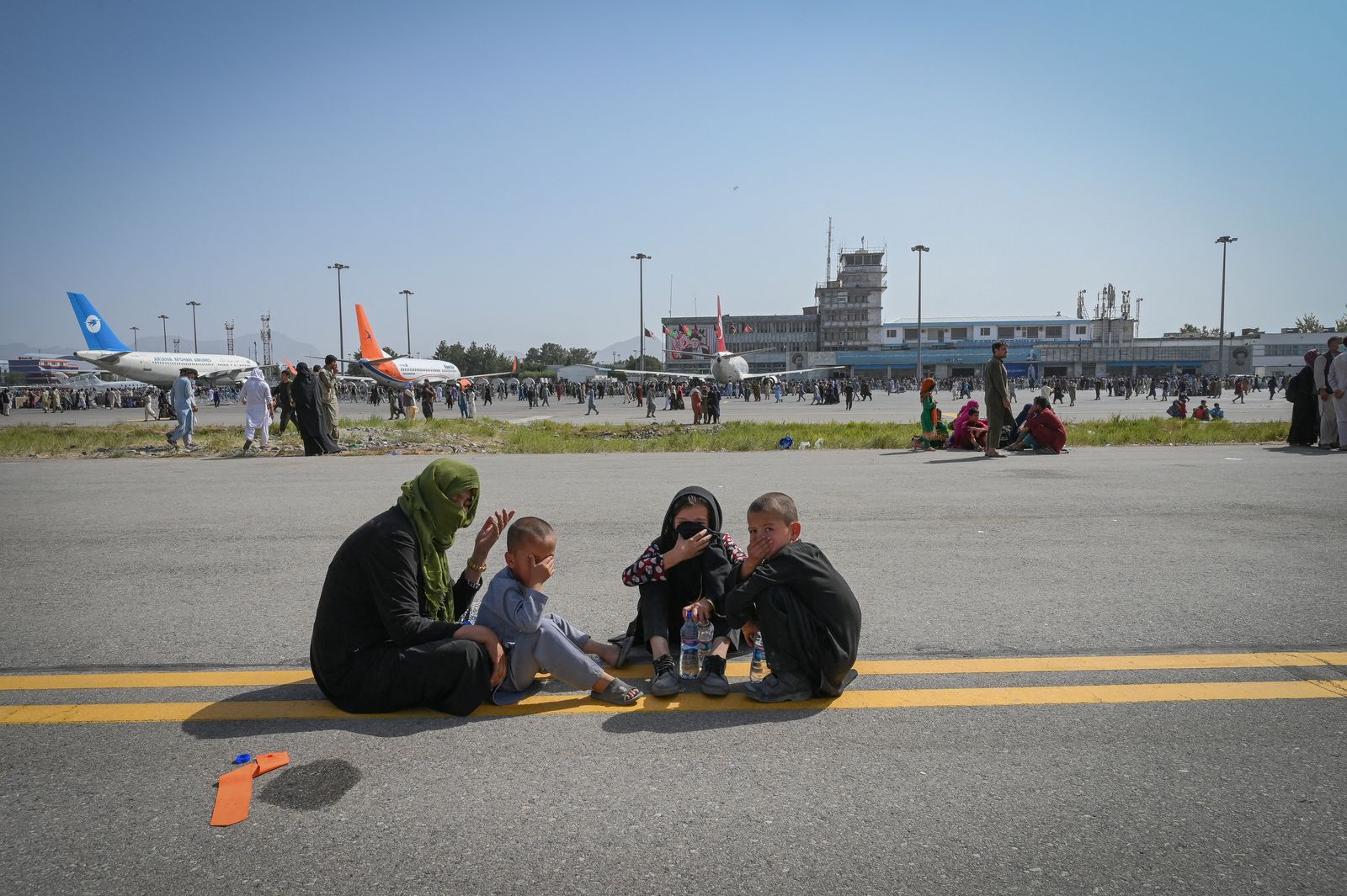 يجلس الأفغان على طول مدرج مطار كابول - 16 أغسطس 2021 - AFP